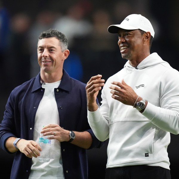 Rory McIlroy and Tiger Woods stand on the green as they watch New York Golf Club and The Bay Golf Club warmup for the inaugural match of the TMRW Golf League, Tuesday, Jan. 7, 2025, in Palm Beach Gardens, Fla. TGL features six teams of four players competing against each other in a tech-infused arena the size of a football field. (AP Photo/Rebecca Blackwell)