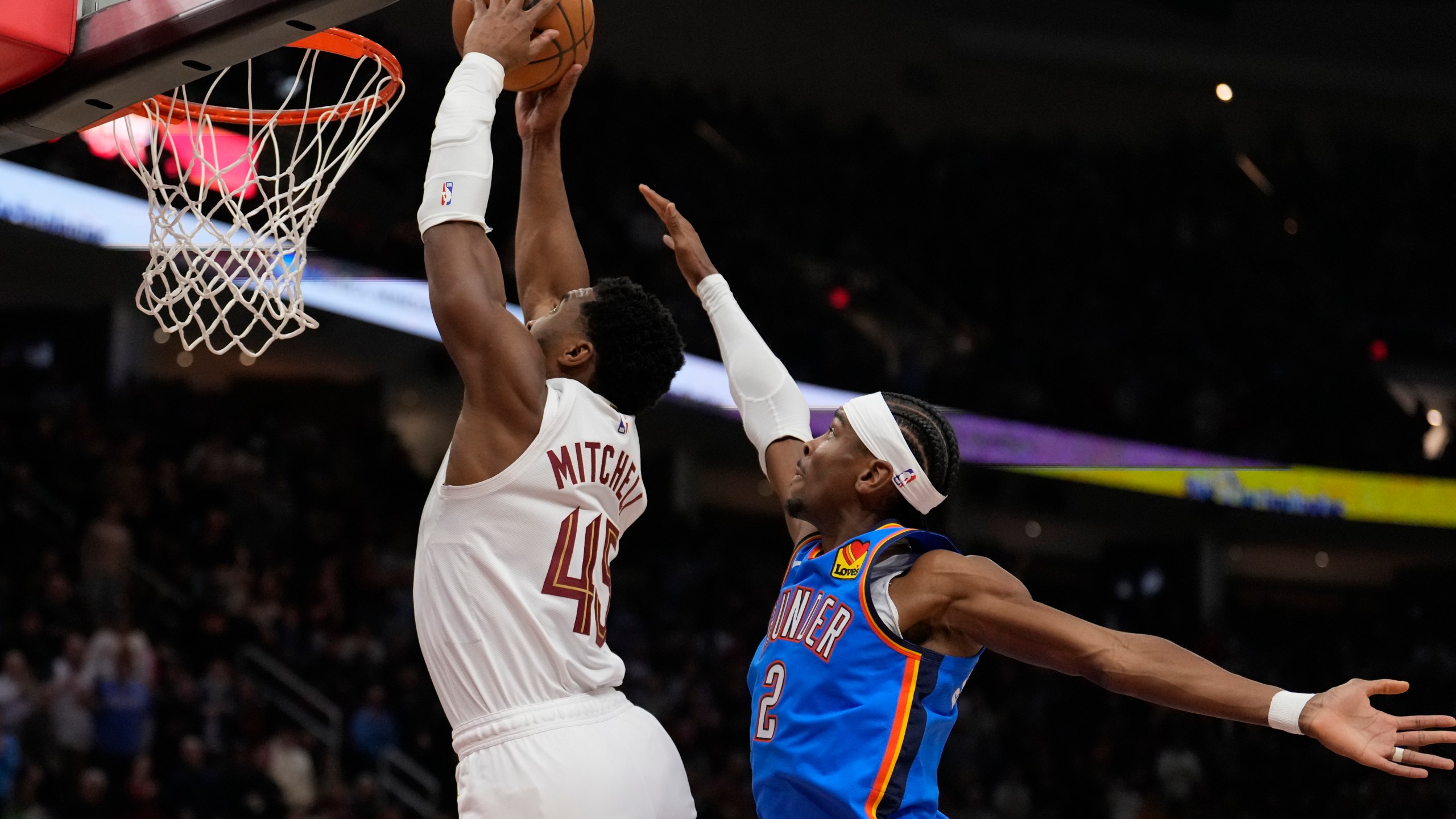 Cleveland Cavaliers guard Donovan Mitchell (45) goes up for a dunk in front of Oklahoma City Thunder guard Shai Gilgeous-Alexander (2) in the first half of an NBA basketball game, Wednesday, Jan. 8, 2025, in Cleveland. (AP Photo/Sue Ogrocki)