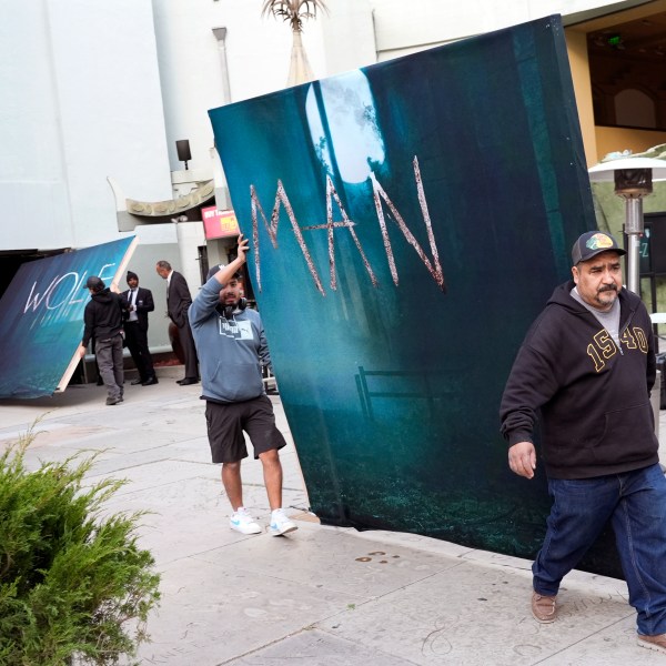 Crew members carry out signs for the new film "Wolf Man" after the premiere was cancelled due to high winds in the area on Tuesday, Jan. 7, 2025, at the TCL Chinese Theatre in Los Angeles. (AP Photo/Chris Pizzello)