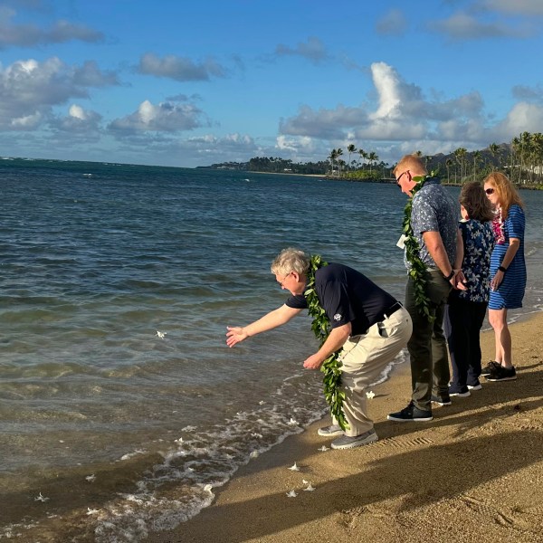 Eric Murray, father of the late PGA Tour player Grayson Murray, tosses a white orchid into the ocean Tuesday, Jan. 7, 2025, during a celebration of life for his son at Waialae Country Club in Honolulu. (AP Photo/Doug Ferguson)