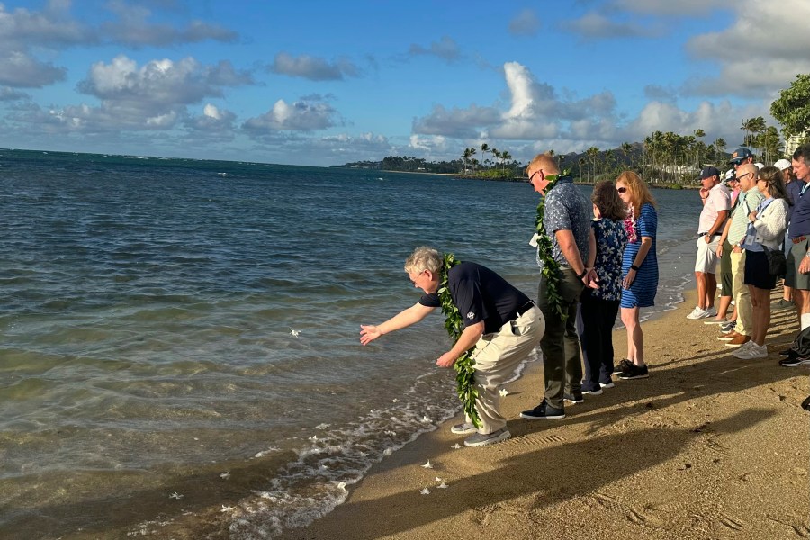 Eric Murray, father of the late PGA Tour player Grayson Murray, tosses a white orchid into the ocean Tuesday, Jan. 7, 2025, during a celebration of life for his son at Waialae Country Club in Honolulu. (AP Photo/Doug Ferguson)