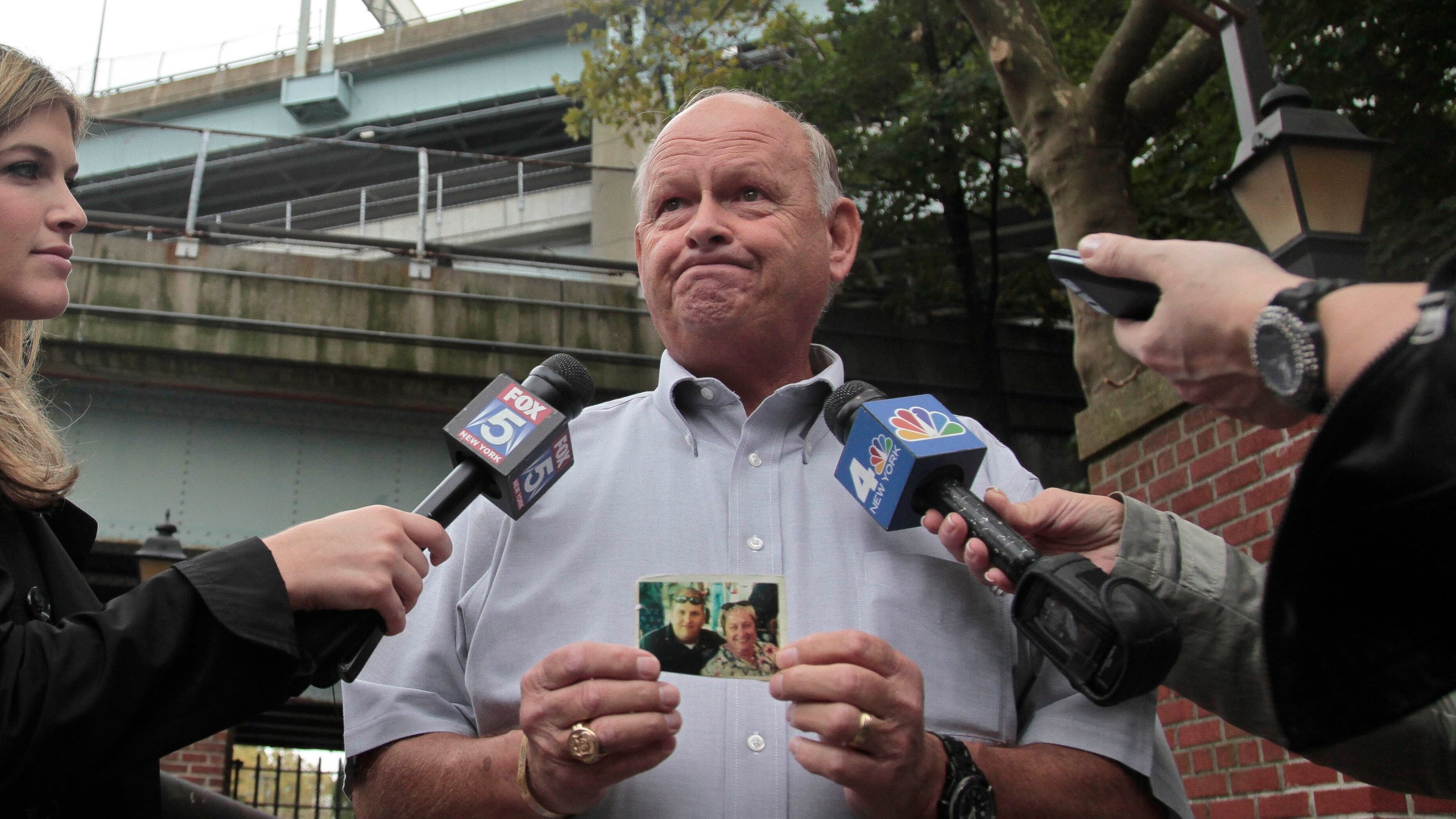 FILE - Ken Fairben holds a photo showing his son Keith, left, a victim of the Sept, 11, attacks, as he talks with reporters Oct. 15, 2012, outside Fort Hamilton Army base in Brooklyn, N.Y. (AP Photo/Bebeto Matthews, File)