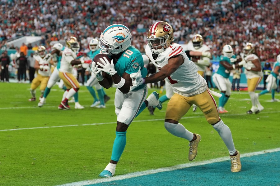 Miami Dolphins wide receiver Tyreek Hill (10) catches a pass for a touchdown as San Francisco 49ers cornerback Charvarius Ward (7) gives him a push during the first half of an NFL football game, Sunday, Dec. 22, 2024, in Miami Gardens, Fla. (AP Photo/Rebecca Blackwell)