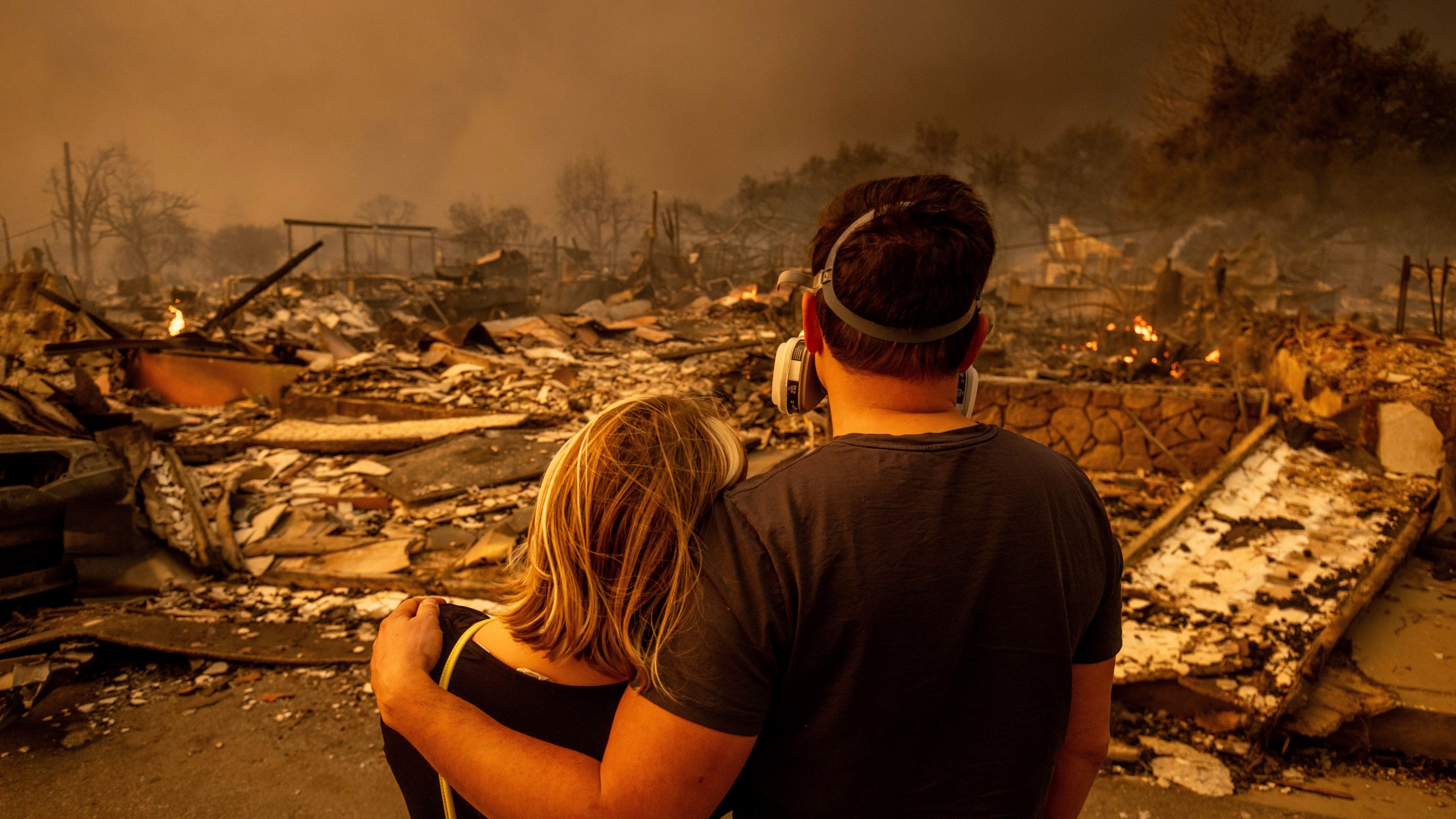 Megan Mantia, left, and her boyfriend Thomas, only first game given, return to Mantia's fire-damaged home after the Eaton Fire swept through the area, Wednesday, Jan. 8, 2025, in Altadena, Calif. (AP Photo/Ethan Swope)