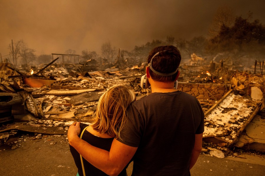 Megan Mantia, left, and her boyfriend Thomas, only first game given, return to Mantia's fire-damaged home after the Eaton Fire swept through the area, Wednesday, Jan. 8, 2025, in Altadena, Calif. (AP Photo/Ethan Swope)