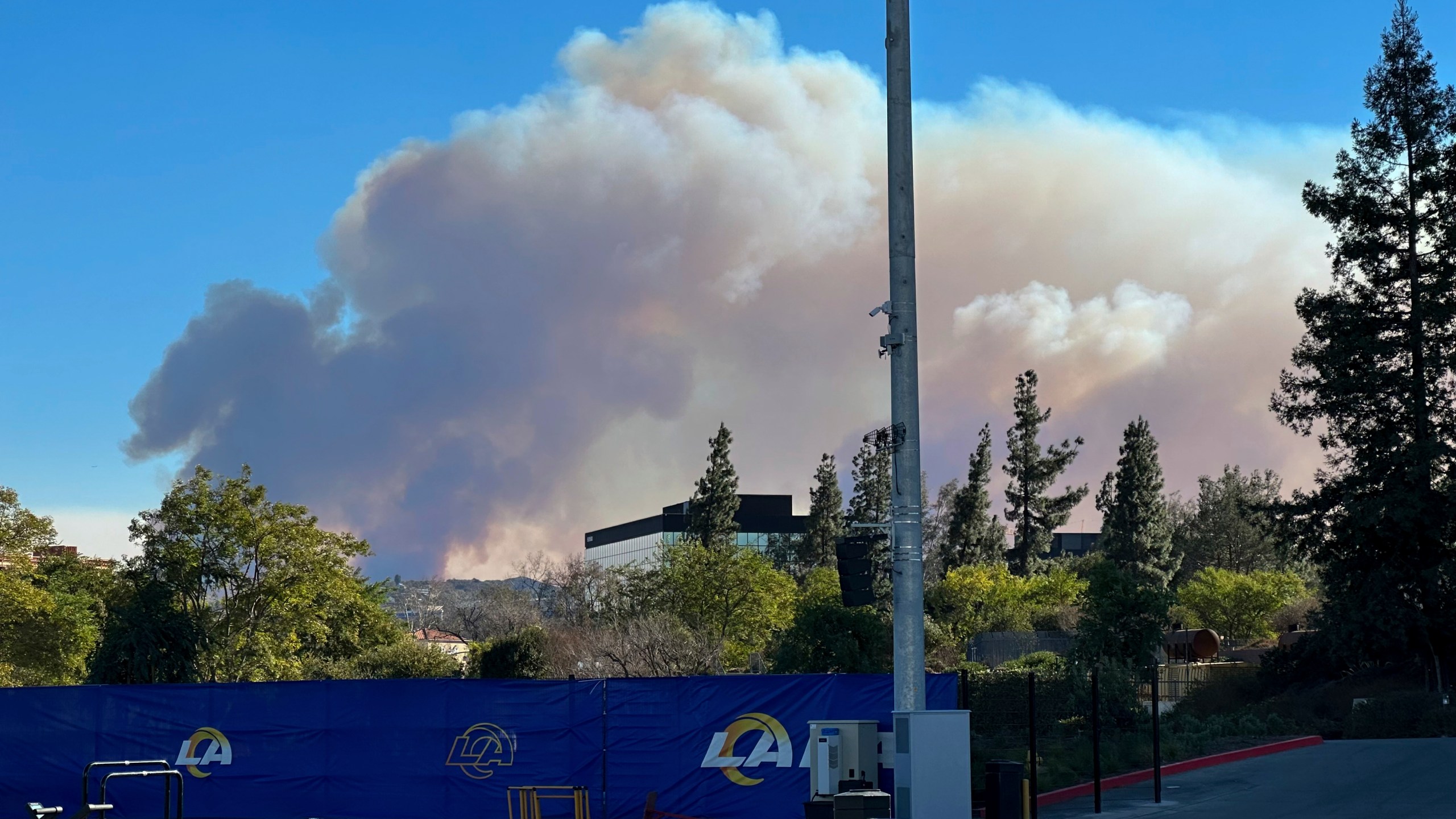 Smokes from a wildfire rises over the Los Angeles Rams NFL football practice facility in the Woodland Hills section of Los Angeles, Thursday, Jan. 9, 2025. (AP Photo/Greg Beacham)