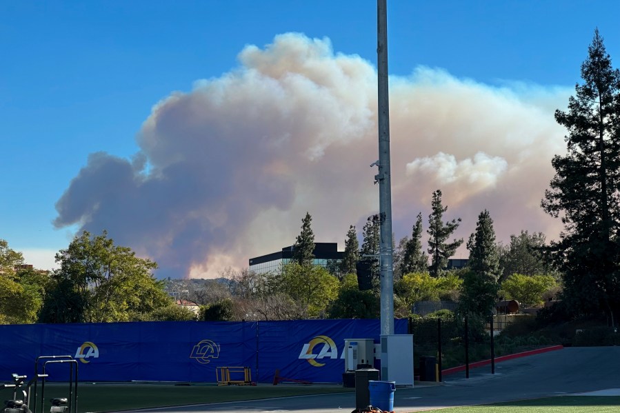 Smokes from a wildfire rises over the Los Angeles Rams NFL football practice facility in the Woodland Hills section of Los Angeles, Thursday, Jan. 9, 2025. (AP Photo/Greg Beacham)