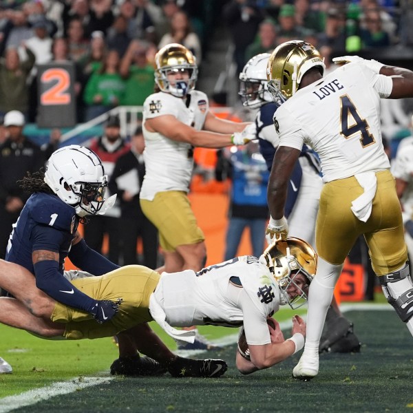 Penn State safety Jaylen Reed (1) attempts to hold Notre Dame quarterback Riley Leonard (13) as he scores a touchdown during the second half of the Orange Bowl NCAA College Football Playoff semifinal game, Thursday, Jan. 9, 2025, in Miami Gardens, Fla. (AP Photo/Rebecca Blackwell)