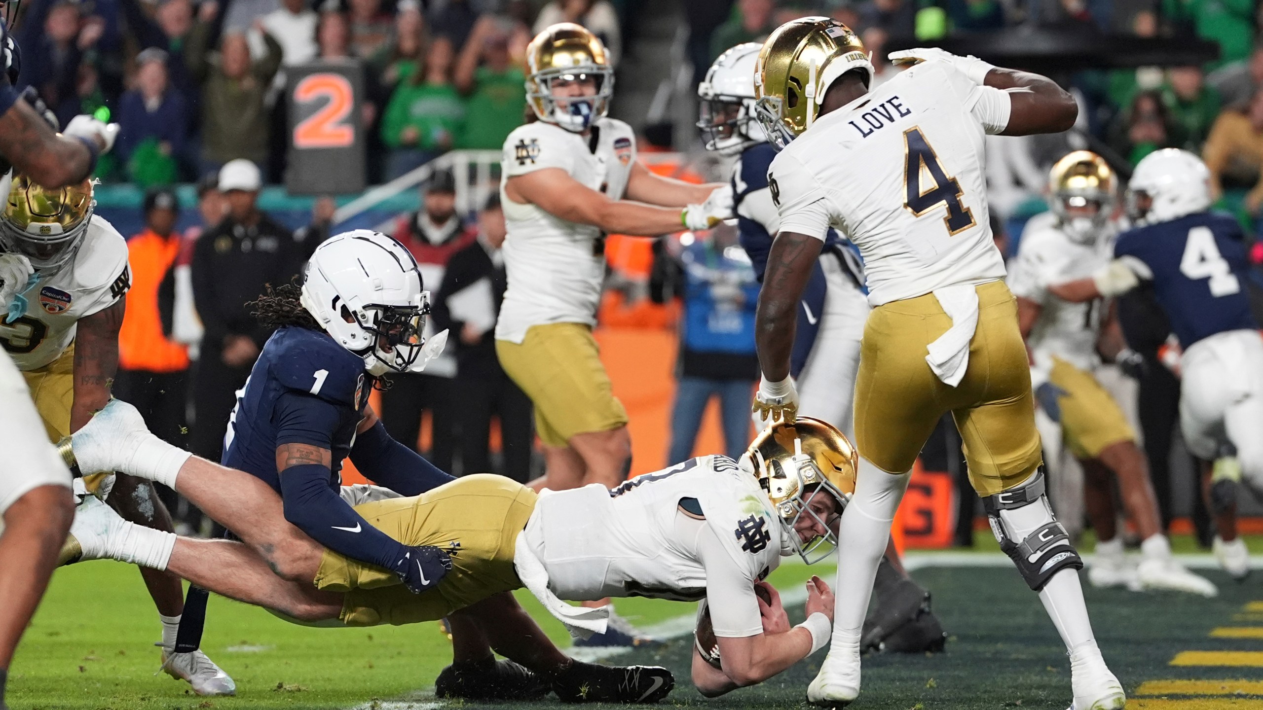 Penn State safety Jaylen Reed (1) attempts to hold Notre Dame quarterback Riley Leonard (13) as he scores a touchdown during the second half of the Orange Bowl NCAA College Football Playoff semifinal game, Thursday, Jan. 9, 2025, in Miami Gardens, Fla. (AP Photo/Rebecca Blackwell)