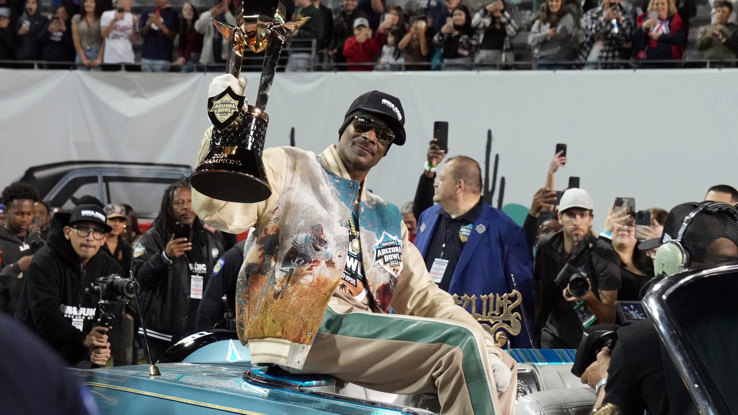 Rapper Snoop Dogg, center, arrives with the trophy after Miami (Ohio) defeated Colorado State in the Arizona Bowl NCAA college football game, Saturday, Dec. 28, 2024, in Tucson, Ariz. (AP Photo/Rick Scuteri)