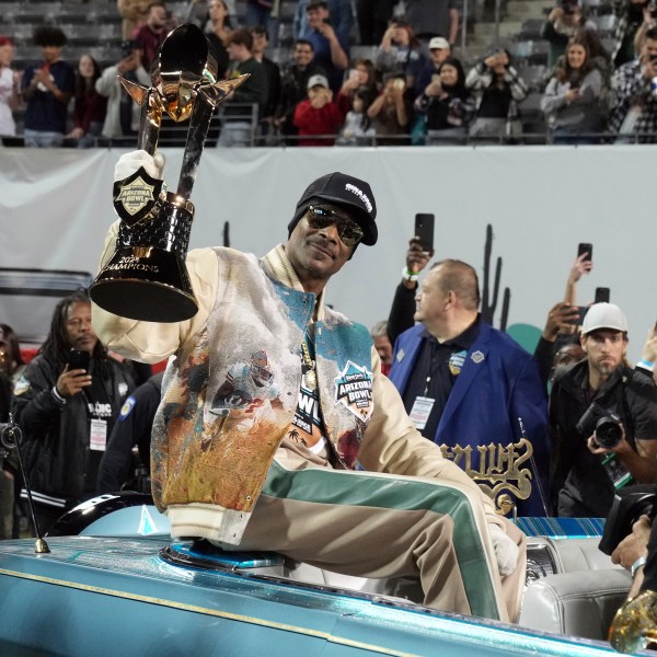 Rapper Snoop Dogg, center, arrives with the trophy after Miami (Ohio) defeated Colorado State in the Arizona Bowl NCAA college football game, Saturday, Dec. 28, 2024, in Tucson, Ariz. (AP Photo/Rick Scuteri)