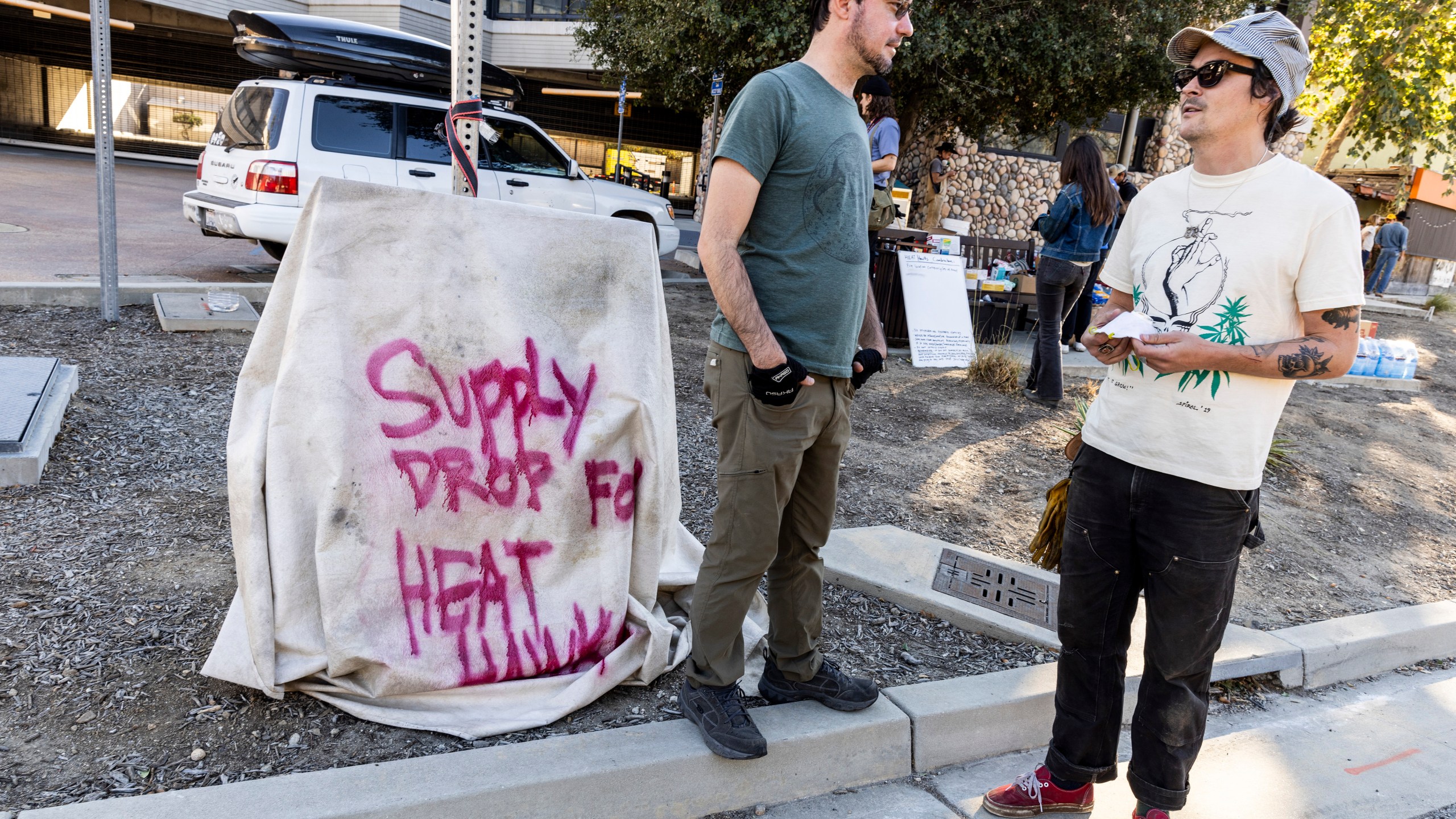 Bobby Ognyanov, left, chats with Cody "Toad" Webb outside Topanga Library as a volunteer group known as the Heat Hawks organizes mutual aid to the community during the Palisades Fire in Topanga, Calif., Thursday, Jan. 9, 2025. (Stephen Lam/San Francisco Chronicle via AP)