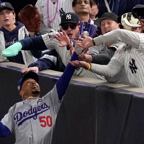 FILE - Fans interfere with a foul ball caught by Los Angeles Dodgers right fielder Mookie Betts during the first inning in Game 4 of the baseball World Series against the New York Yankees, Tuesday, Oct. 29, 2024, in New York. (AP Photo/Ashley Landis, File)