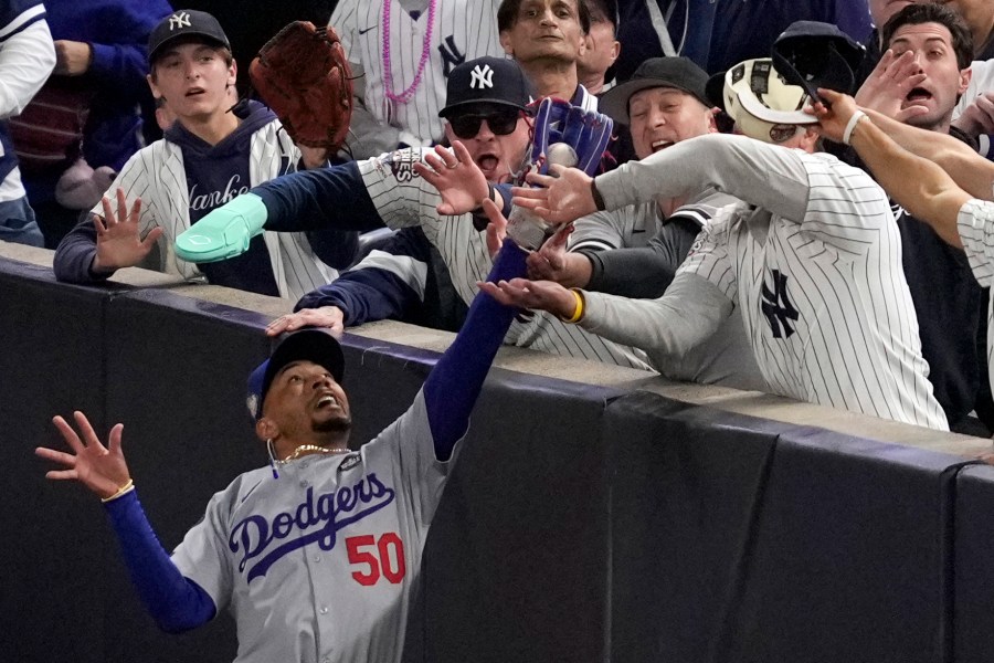 FILE - Fans interfere with a foul ball caught by Los Angeles Dodgers right fielder Mookie Betts during the first inning in Game 4 of the baseball World Series against the New York Yankees, Tuesday, Oct. 29, 2024, in New York. (AP Photo/Ashley Landis, File)