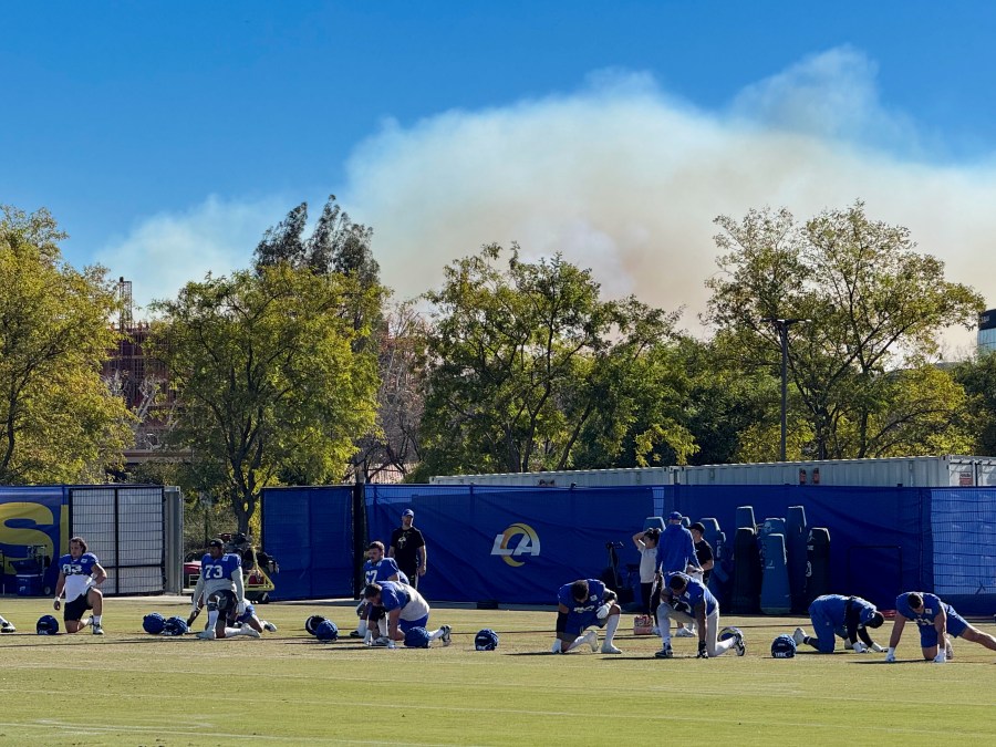 The Los Angeles Rams NFL football team practices under a plume of smoke from the Palisades Fire in preparation for a playoff game against the Minnesota Vikings in the Woodland Hills section of Los Angeles, Friday, Jan. 10, 2025. (AP Photo/Dan Greenspan)