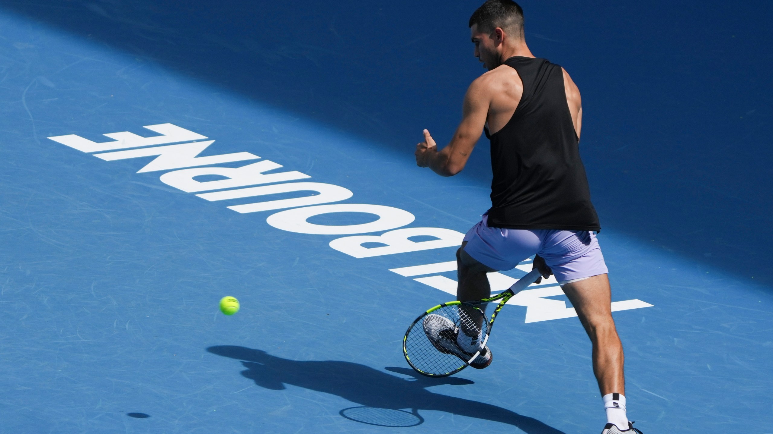 Spain's Carlos Alcaraz plays a shot between his legs during a practice session ahead of the Australian Open tennis championship in Melbourne, Australia, Thursday, Jan. 9, 2025. (AP Photo/Mark Baker)