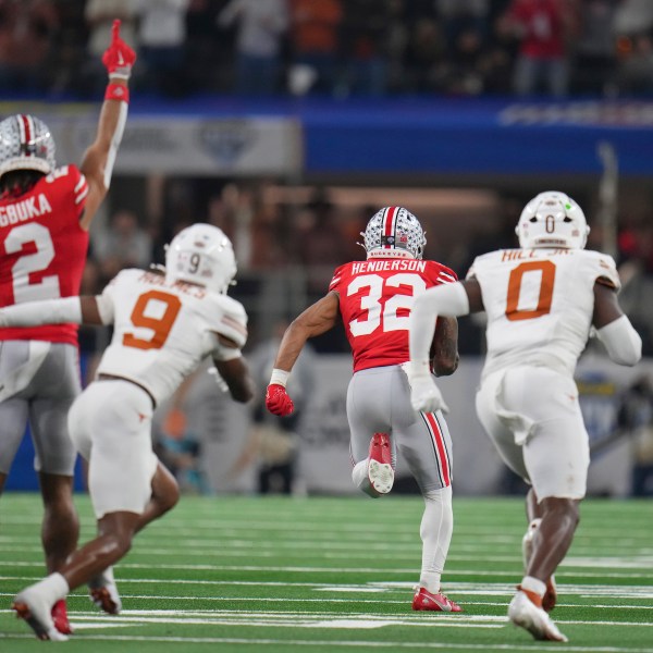 Ohio State wide receiver Emeka Egbuka (2) reacts as running back TreVeyon Henderson (32) runs past Texas defensive back Gavin Holmes (9) and linebacker Anthony Hill Jr. (0) to score during the first half of the Cotton Bowl College Football Playoff semifinal game, Friday, Jan. 10, 2025, in Arlington, Texas. (AP Photo/Julio Cortez)