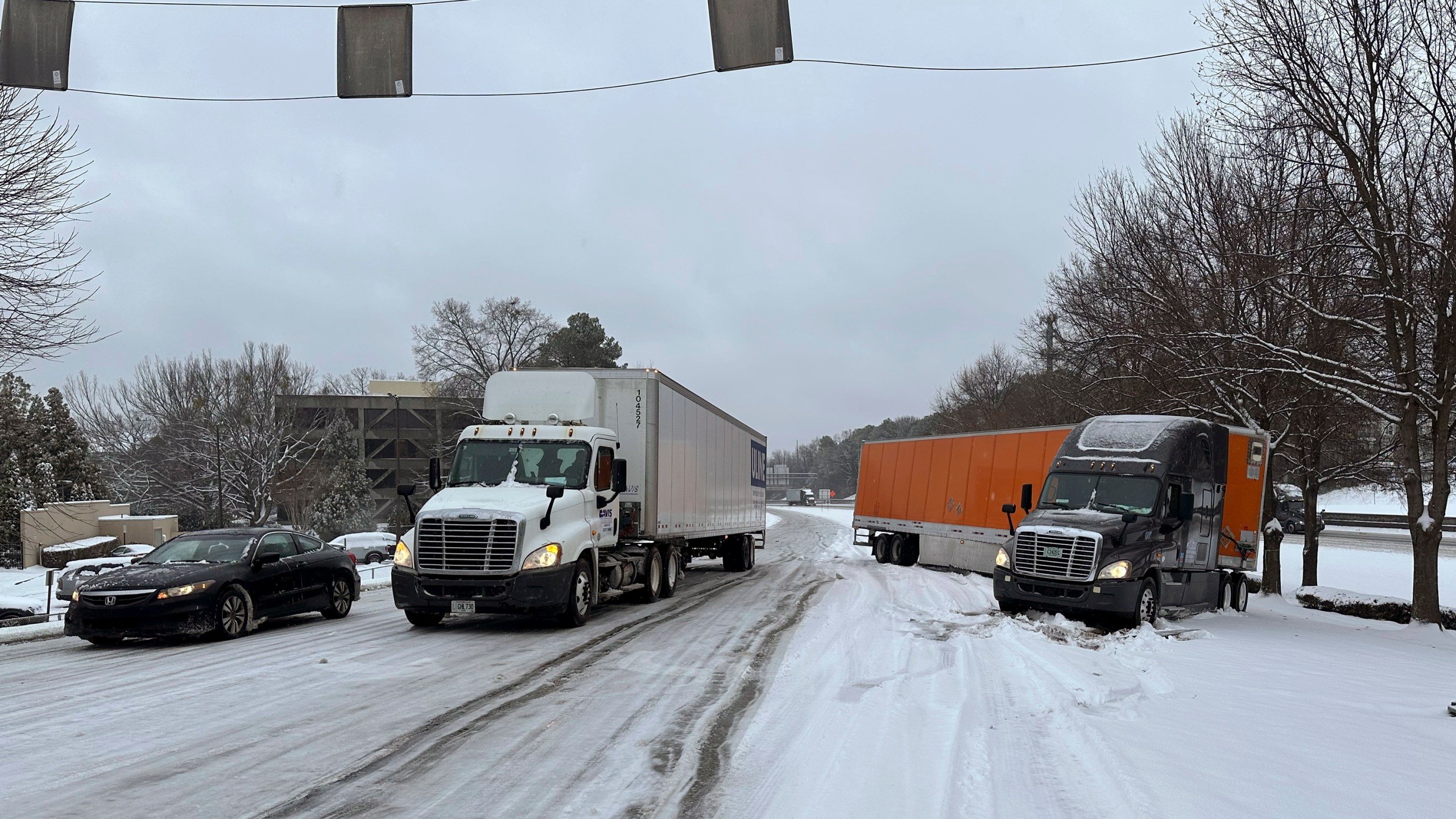 A truck is jackknifed as another spins its wheels on a slushy offramp off Interstate 285 northeast of downtown in Atlanta on Friday, Jan. 10, 2025. (AP Photo/Jeff Amy)