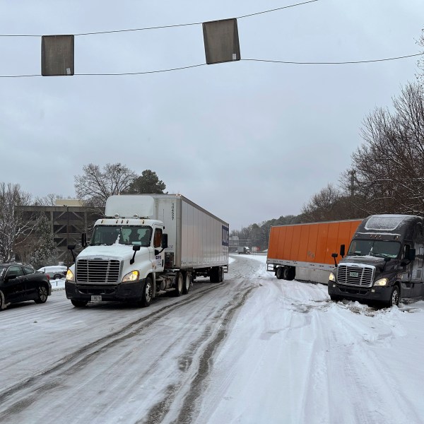 A truck is jackknifed as another spins its wheels on a slushy offramp off Interstate 285 northeast of downtown in Atlanta on Friday, Jan. 10, 2025. (AP Photo/Jeff Amy)