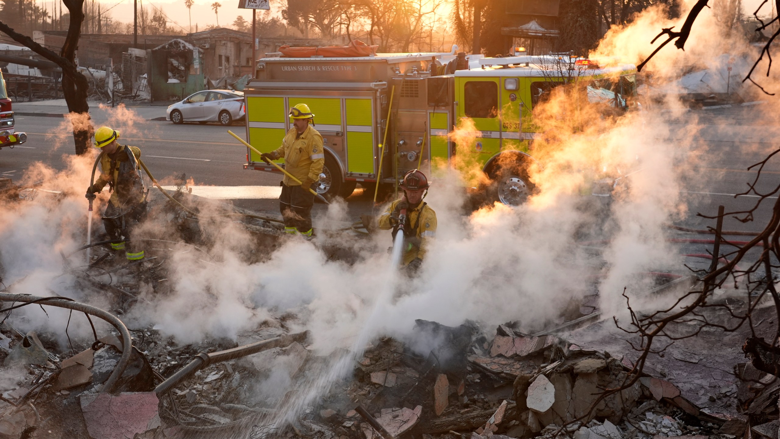 Firefighters extinguish burning embers at the site of a structure on Lake Avenue destroyed by the Eaton Fire, Friday, Jan. 10, 2025, in Altadena, Calif. (AP Photo/Chris Pizzello)