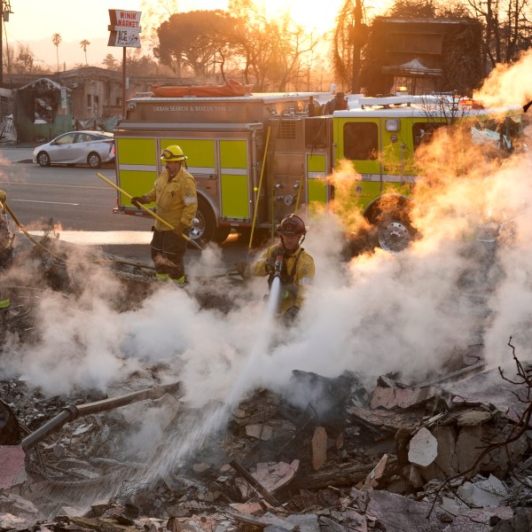 Firefighters extinguish burning embers at the site of a structure on Lake Avenue destroyed by the Eaton Fire, Friday, Jan. 10, 2025, in Altadena, Calif. (AP Photo/Chris Pizzello)