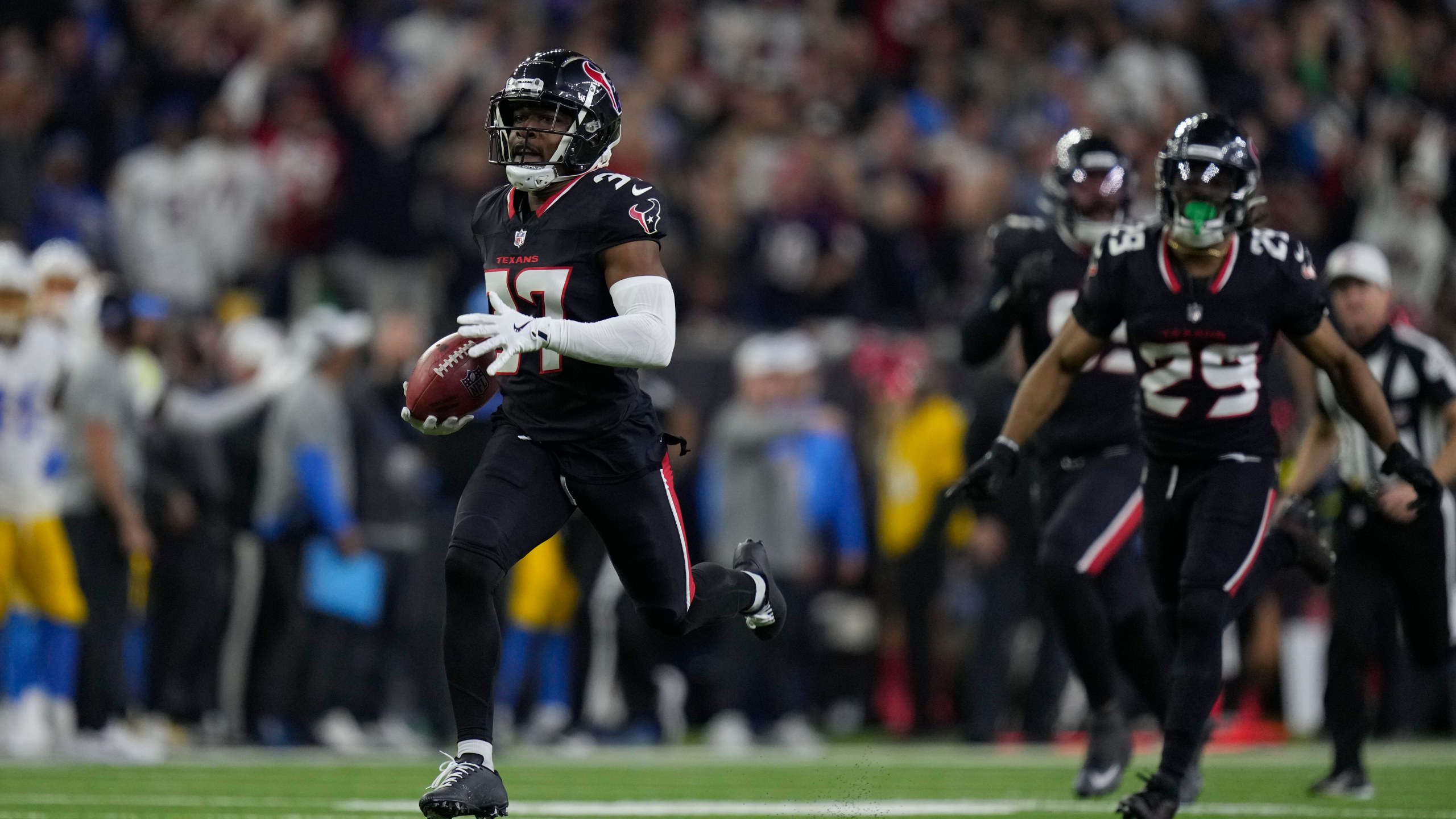 Houston Texans' D'Angelo Ross (37) returns a blocked extra-point attempt by Los Angeles Chargers place kicker Cameron Dicker (11) for two-points during the second half of an NFL wild-card playoff football game Saturday, Jan. 11, 2025, in Houston. (AP Photo/Eric Christian Smith)