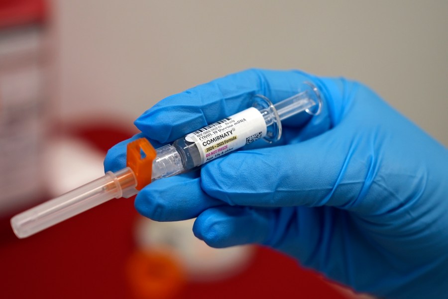 FILE - A pharmacist holds a COVID-19 vaccine at a pharmacy in New York, on Sept. 24, 2024. (AP Photo/Mary Conlon, File)