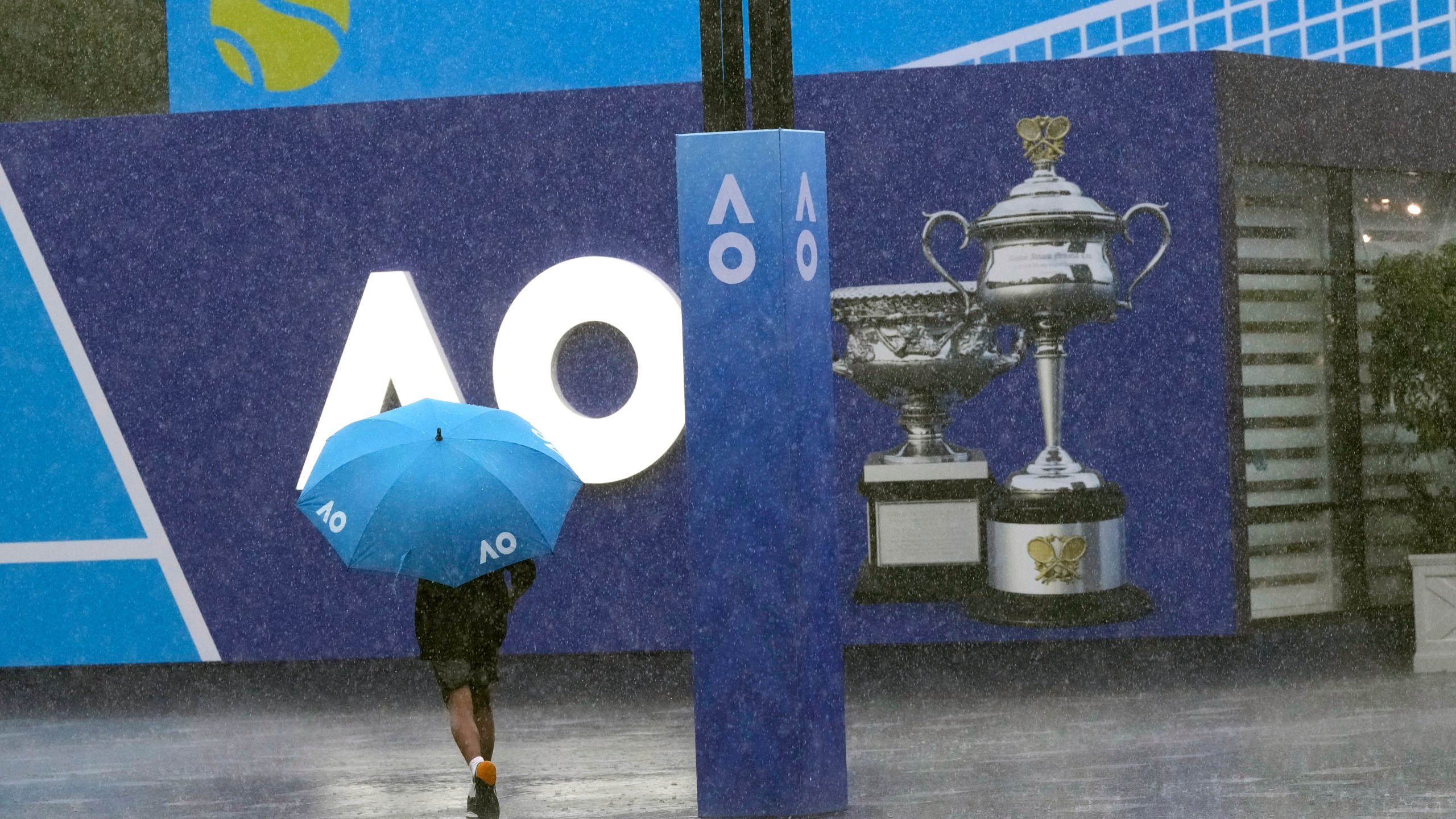 A spectator runs as play is suspended for rain during first round matches at the Australian Open tennis championship in Melbourne, Australia, Sunday, Jan. 12, 2025. (AP Photo/Manish Swarup)