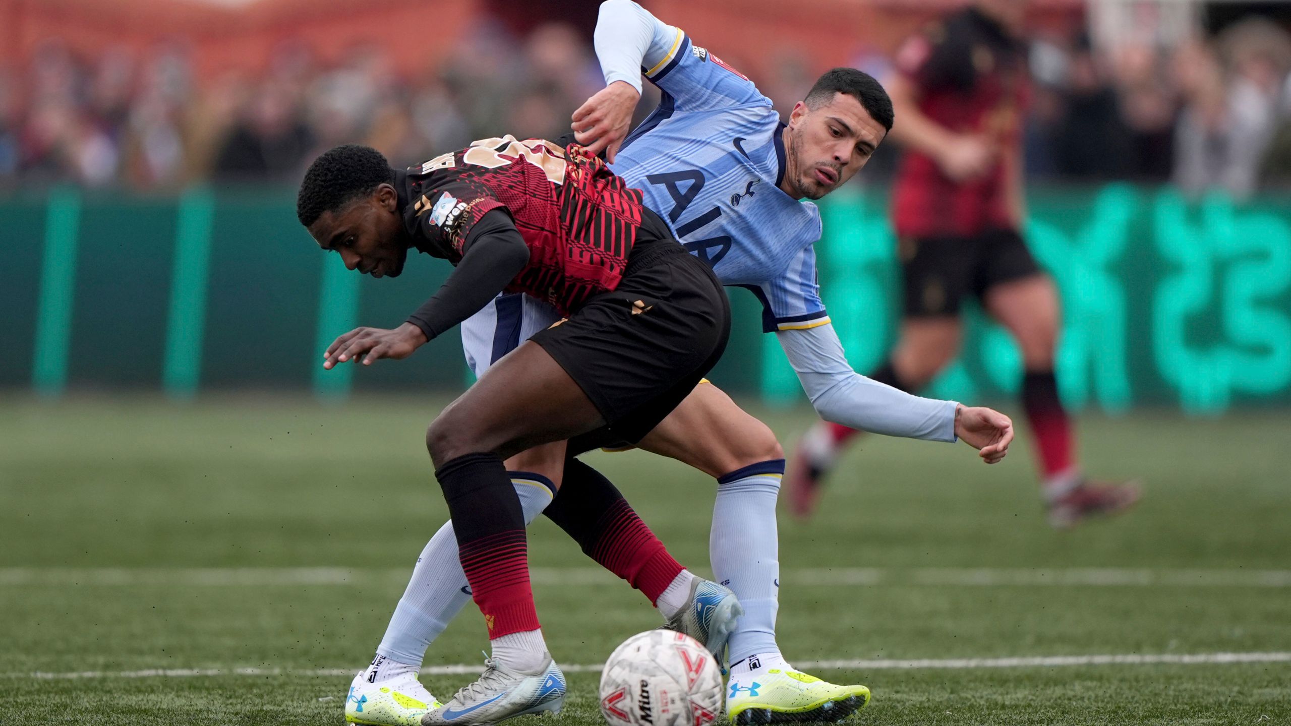 Tamworth's Beck-Ray Enoru, left, and Tottenham Hotspur's Pedro Porro battle for the ball during the English FA Cup third round match at The Lamb Ground, Tamworth, England, Sunday Jan. 12, 2025. (Joe Giddens/PA via AP)