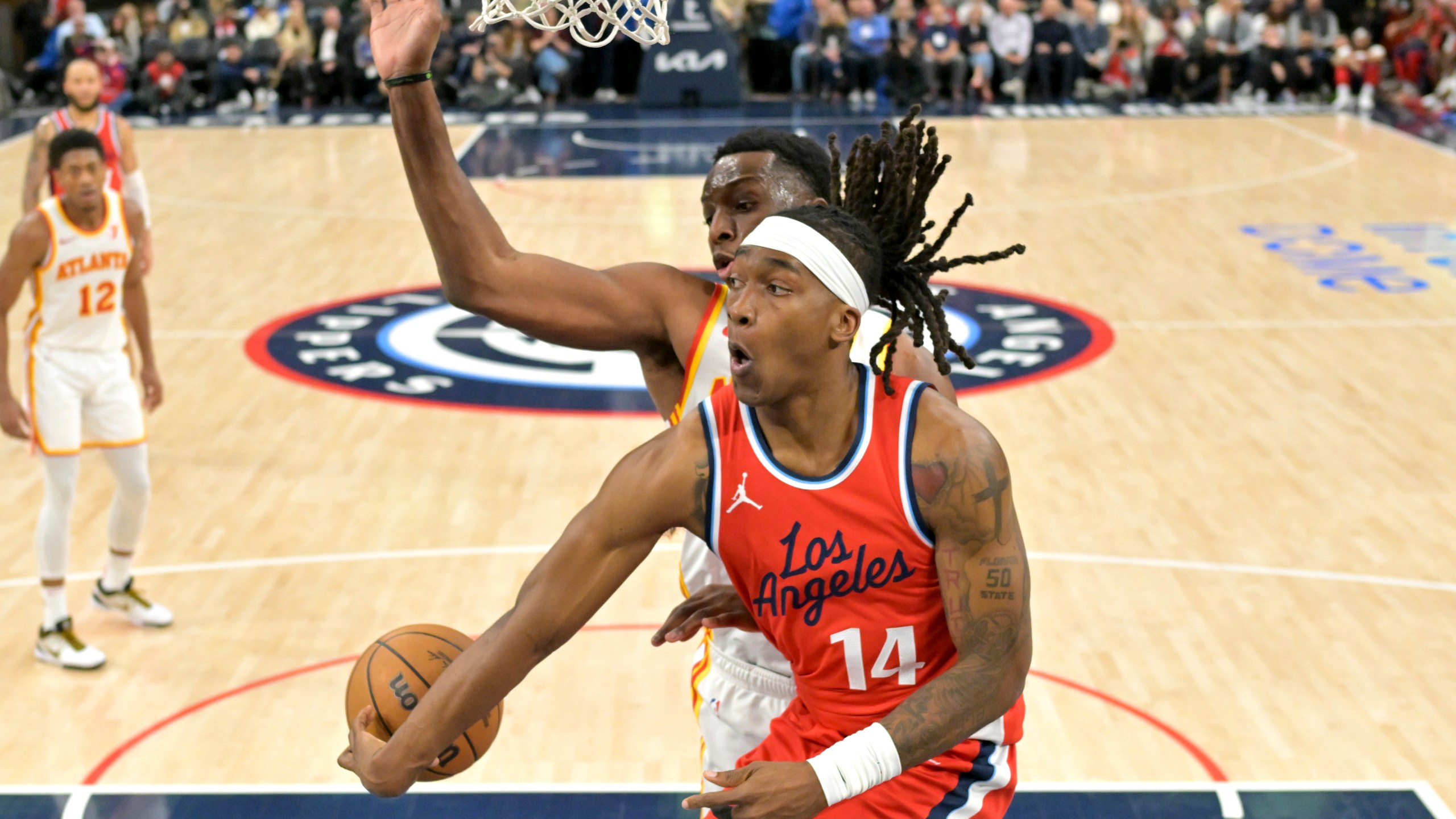 Los Angeles Clippers guard Terance Mann (14) makes a pass around Atlanta Hawks forward Onyeka Okongwu during the second half of an NBA basketball game Saturday, Jan. 4, 2025, in Los Angeles. (AP Photo/Jayne-Kamin-Oncea)