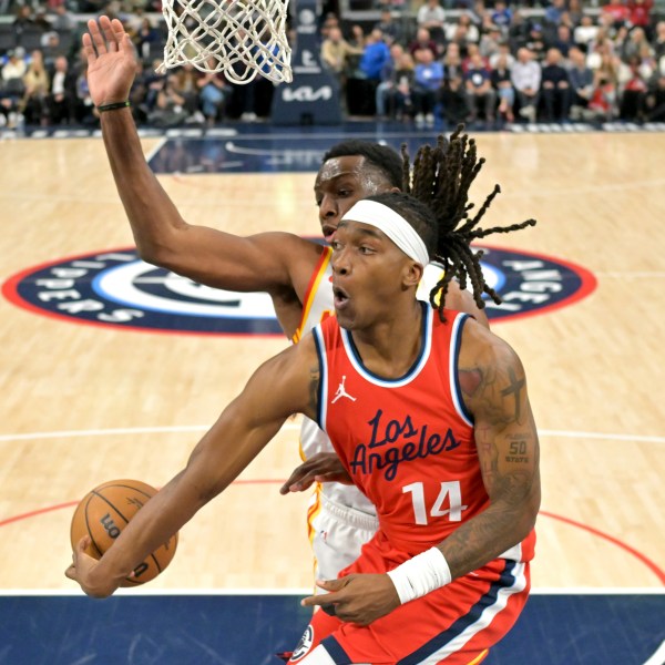 Los Angeles Clippers guard Terance Mann (14) makes a pass around Atlanta Hawks forward Onyeka Okongwu during the second half of an NBA basketball game Saturday, Jan. 4, 2025, in Los Angeles. (AP Photo/Jayne-Kamin-Oncea)