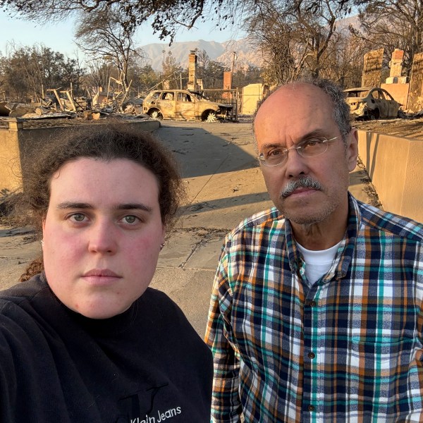 Vanessa Prata and her father, Aluizio Prata, pose for a self-portrait in Altadena, Calif., on Saturday, Jan. 11, 2025, with damage from the Eaton fire behind them. (Vanessa Prata via AP)