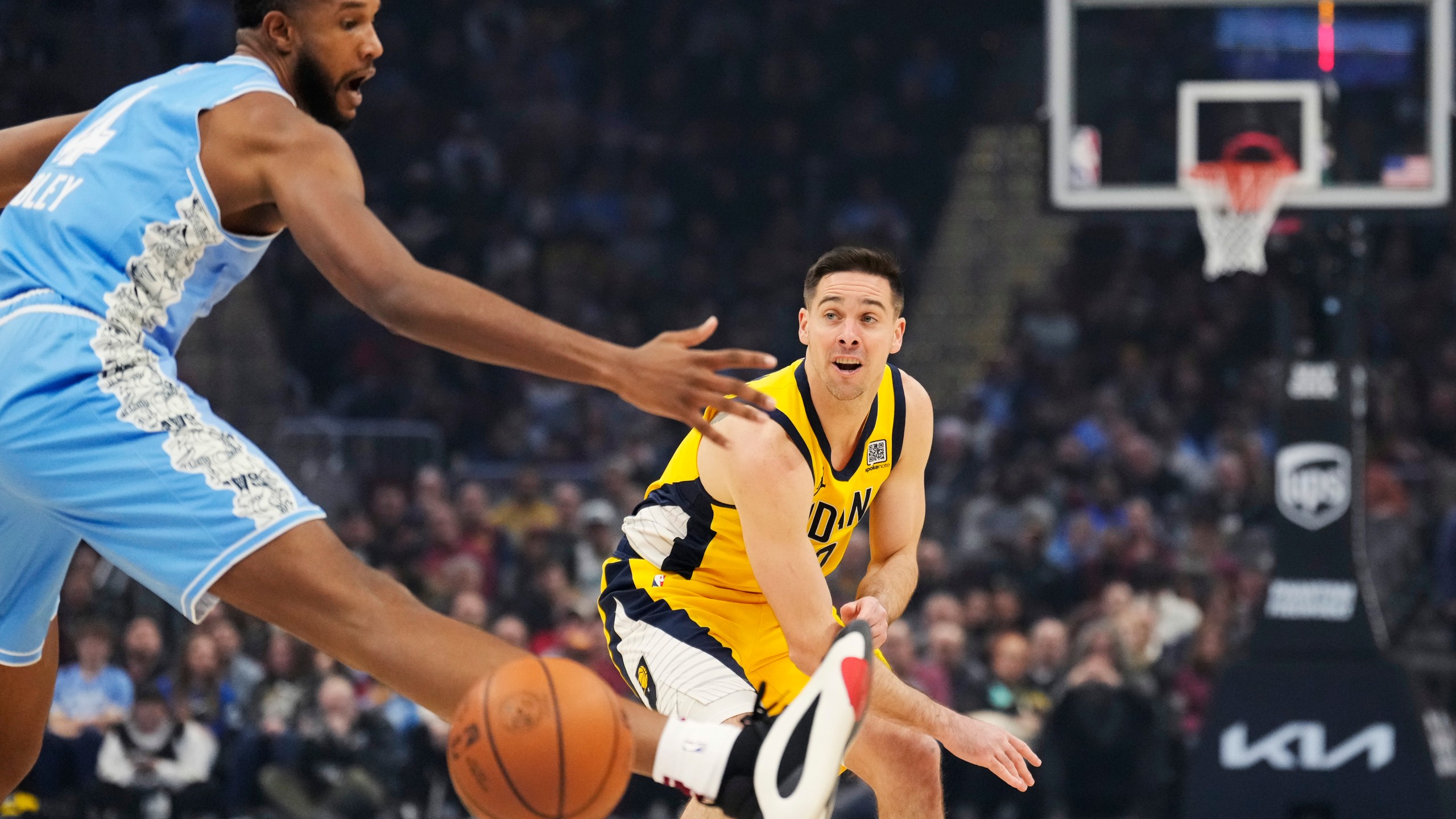 Indiana Pacers guard T.J. McConnell, right, passes in front of Cleveland Cavaliers forward Evan Mobley, left, in the first half of an NBA basketball game, Sunday, Jan. 12, 2025, in Cleveland. (AP Photo/Sue Ogrocki)