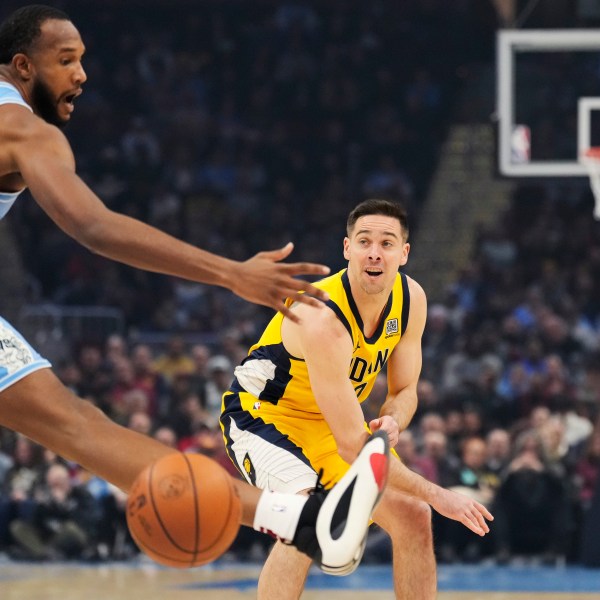 Indiana Pacers guard T.J. McConnell, right, passes in front of Cleveland Cavaliers forward Evan Mobley, left, in the first half of an NBA basketball game, Sunday, Jan. 12, 2025, in Cleveland. (AP Photo/Sue Ogrocki)