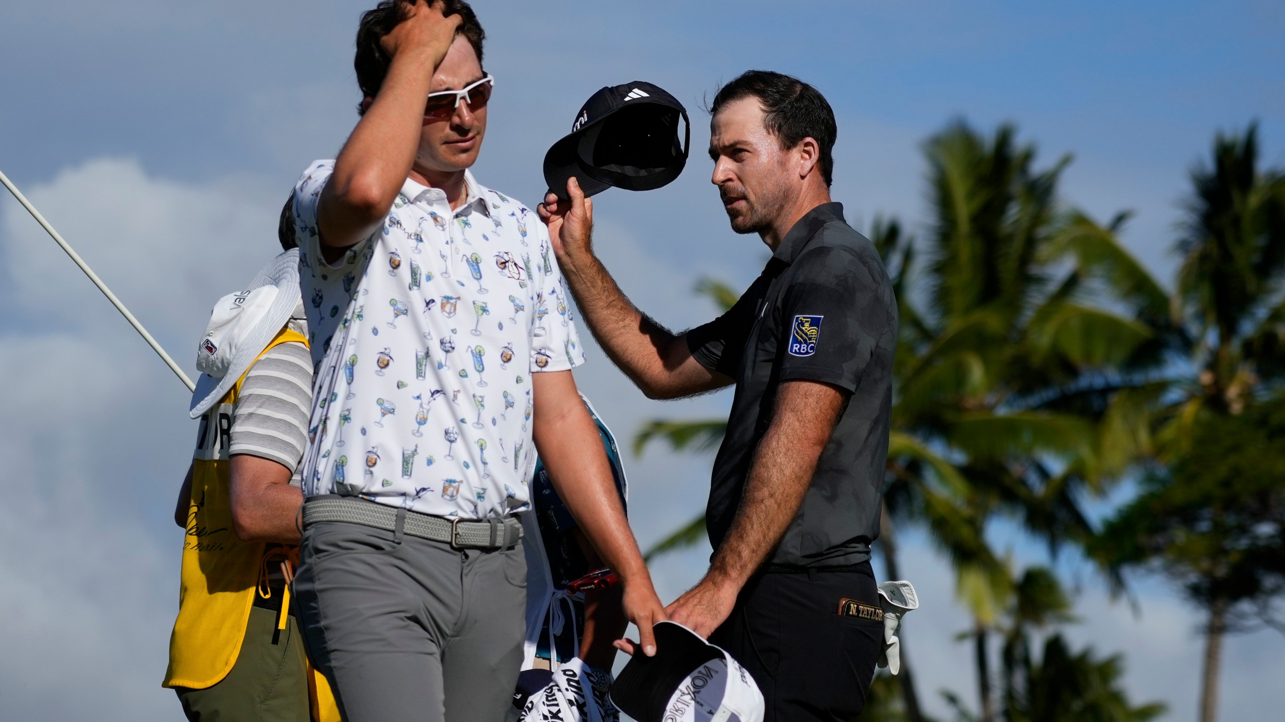 Nico Echavarria, left, of Columbia, walks away as Nick Taylor, of Canada, celebrates after winning their playoff in the final round of the Sony Open golf event, Sunday, Jan. 12, 2025, at Waialae Country Club in Honolulu. (AP Photo/Matt York)