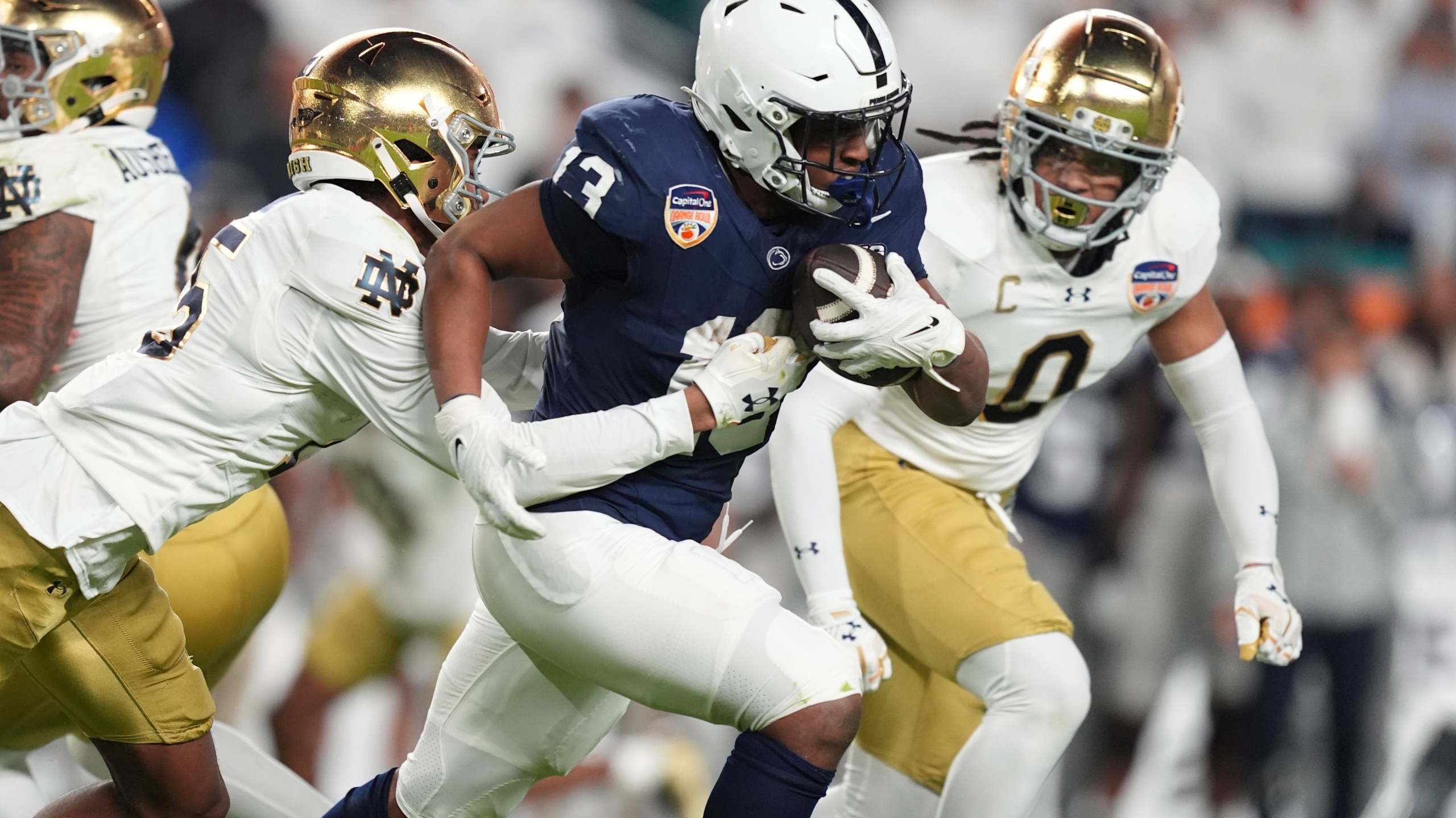 Notre Dame cornerback Leonard Moore (15) grabs Penn State running back Kaytron Allen (13) during the first half of the Orange Bowl NCAA College Football Playoff semifinal game, Thursday, Jan. 9, 2025, in Miami Gardens, Fla. (AP Photo/Rebecca Blackwell)