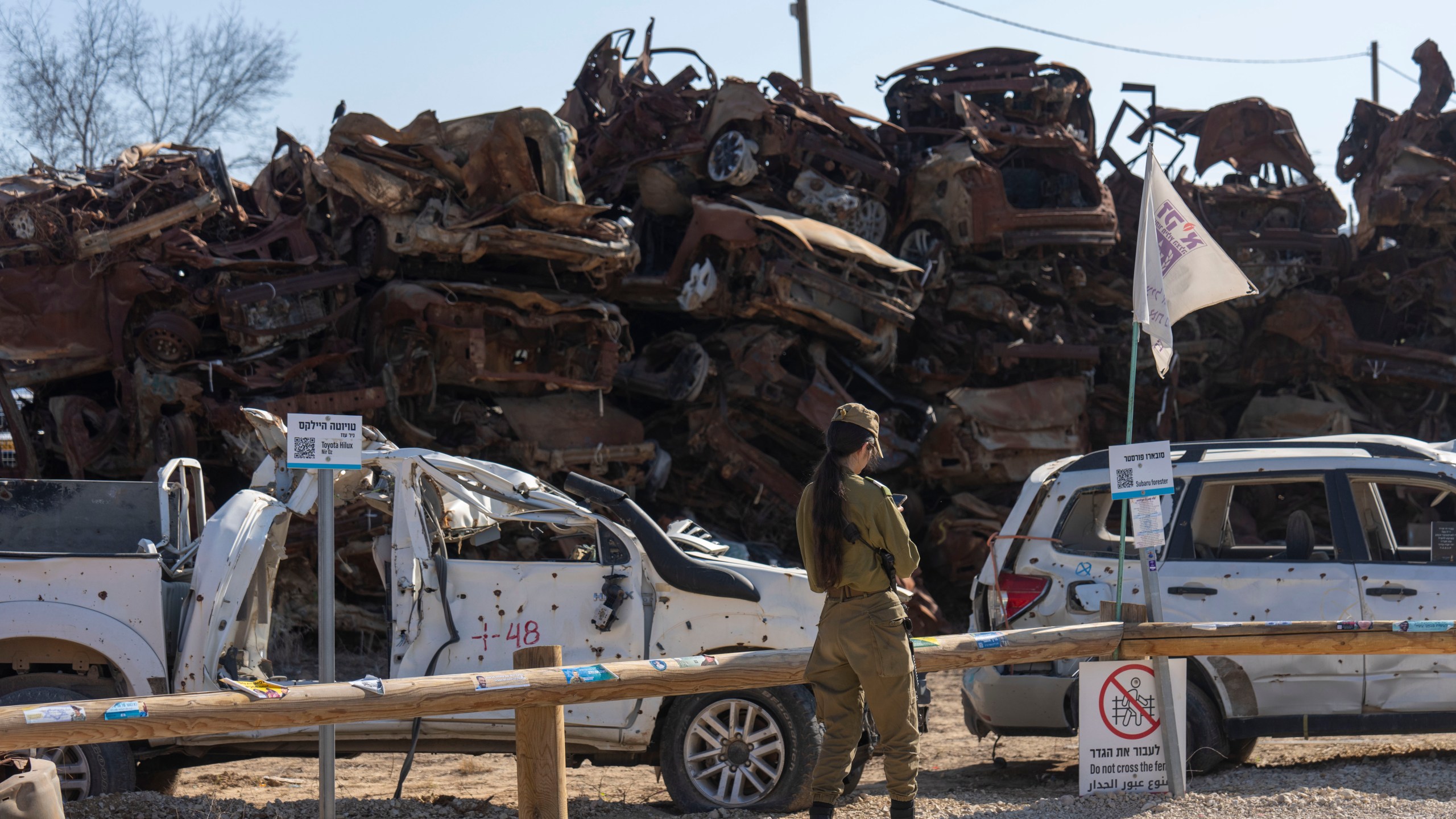 An Israeli soldier looks at charred vehicles burned in the Oct. 7 , 2023, cross-border attacks by Hamas militants outside the town of Netivot, southern Israel, Monday, Jan. 13, 2025. (AP Photo/Ariel Schalit)