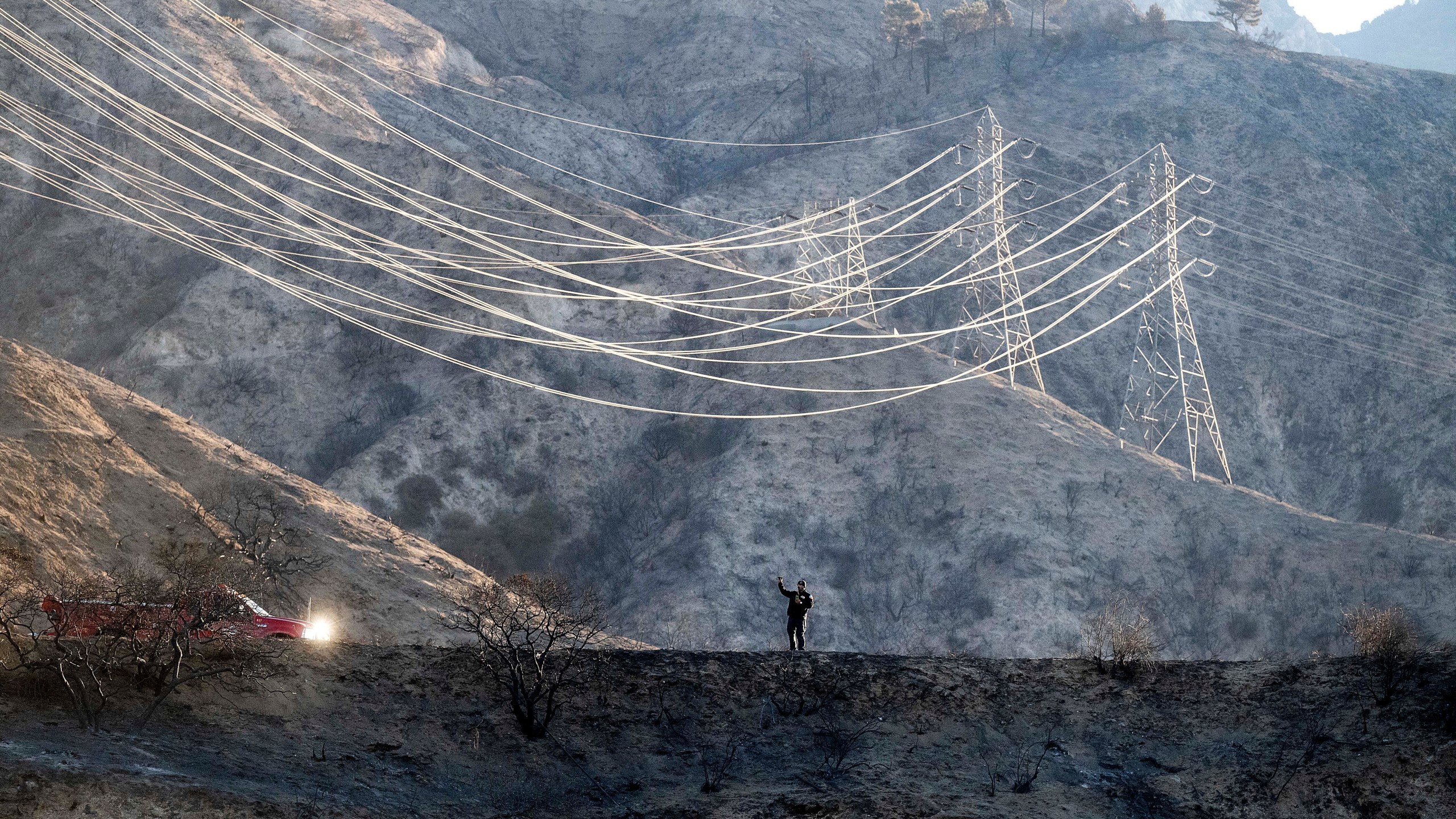 A firefighter takes weather readings while standing on a scorched ridgetop above the Eaton Fire in Angeles National Forest on Monday, Jan. 13, 2025. (AP Photo/Noah Berger)