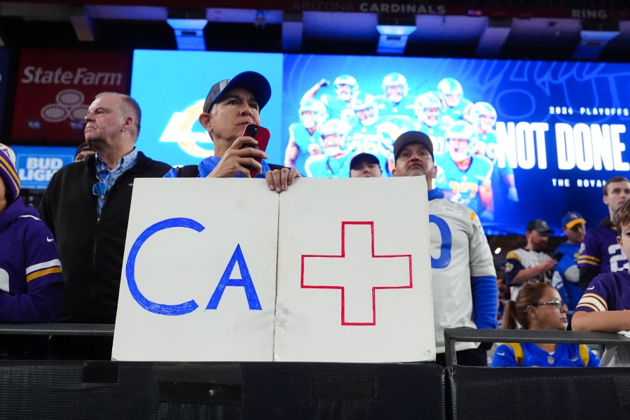 A Los Angeles Rams fan holds a sign b before an NFL wild card playoff football game against the Minnesota Vikings, Monday, Jan. 13, 2025, in Glendale, Ariz. (AP Photo/Ross D. Franklin)