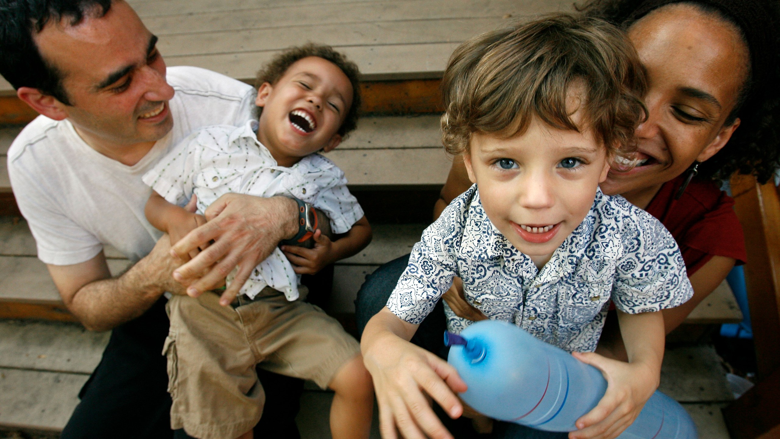 FILE - Alex Diaz-Asper, left, and his wife Rachel Lerman, far right, play with their twin boys, Alejandro, center left, and Miguel , 3, at their home in Washington, June 11, 2008. (AP Photo/Jacquelyn Martin, File)