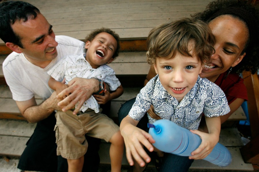 FILE - Alex Diaz-Asper, left, and his wife Rachel Lerman, far right, play with their twin boys, Alejandro, center left, and Miguel , 3, at their home in Washington, June 11, 2008. (AP Photo/Jacquelyn Martin, File)