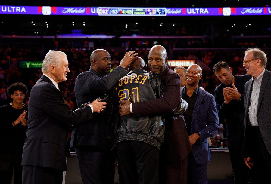 Former Los Angeles Lakers player Michel Cooper, center, is mobbed by coach Pat Riley, left, Magic Johnson, James Worthy, Byron Scott, Vlade Divac and Kurt Rambis after his jersey was retired during a ceremony during halftime in an NBA basketball game between the Lakers and the San Antonio Spurs, Monday, Jan. 13, 2025, in Los Angeles. (AP Photo/Kevork Djansezian)