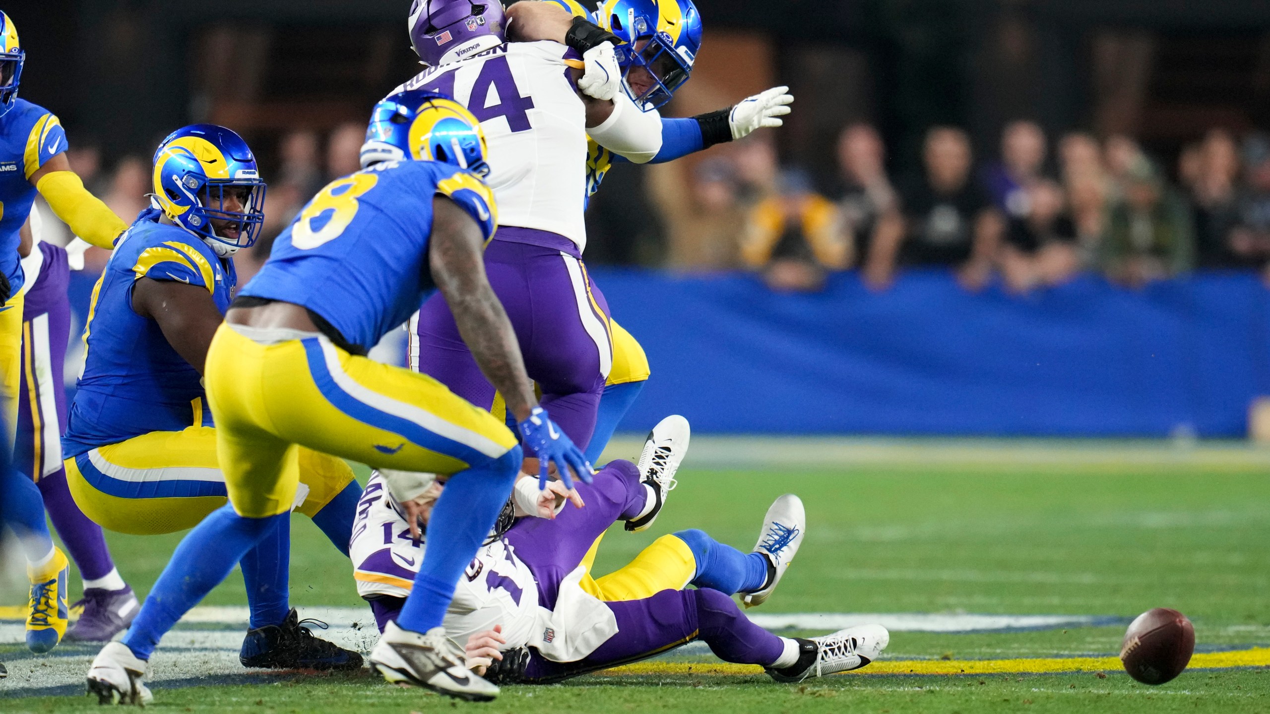 Los Angeles Rams linebacker Jared Verse (8) looks to pick up a Minnesota Vikings quarterback Sam Darnold (14) fumble caused by Ahkello Witherspoon (4) during the first half of an NFL wild card playoff football game, Monday, Jan. 13, 2025, in Glendale, Ariz.Verse returned the fumble for a 57-yard touchdown. (AP Photo/Ross D. Franklin)