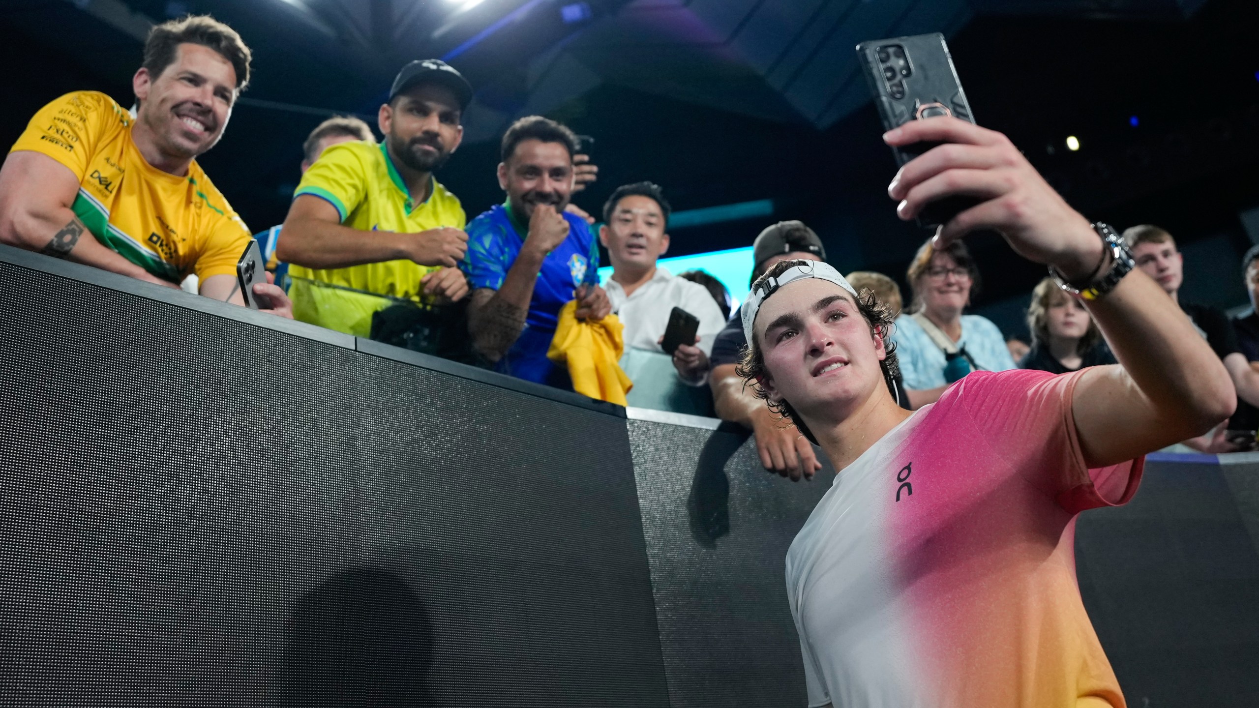 Joao Fonseca of Brazil takes a selfie with fans after defeating Andrey Rublev of Russia in their first round match at the Australian Open tennis championship in Melbourne, Australia, Tuesday, Jan. 14, 2025. (AP Photo/Asanka Brendon Ratnayake)