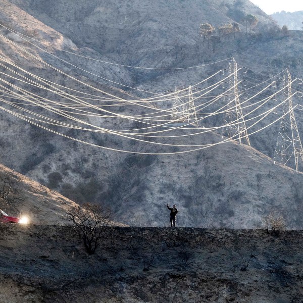 A firefighter takes weather readings while standing on a scorched ridgetop above the Eaton Fire in Angeles National Forest on Monday, Jan. 13, 2025. (AP Photo/Noah Berger)