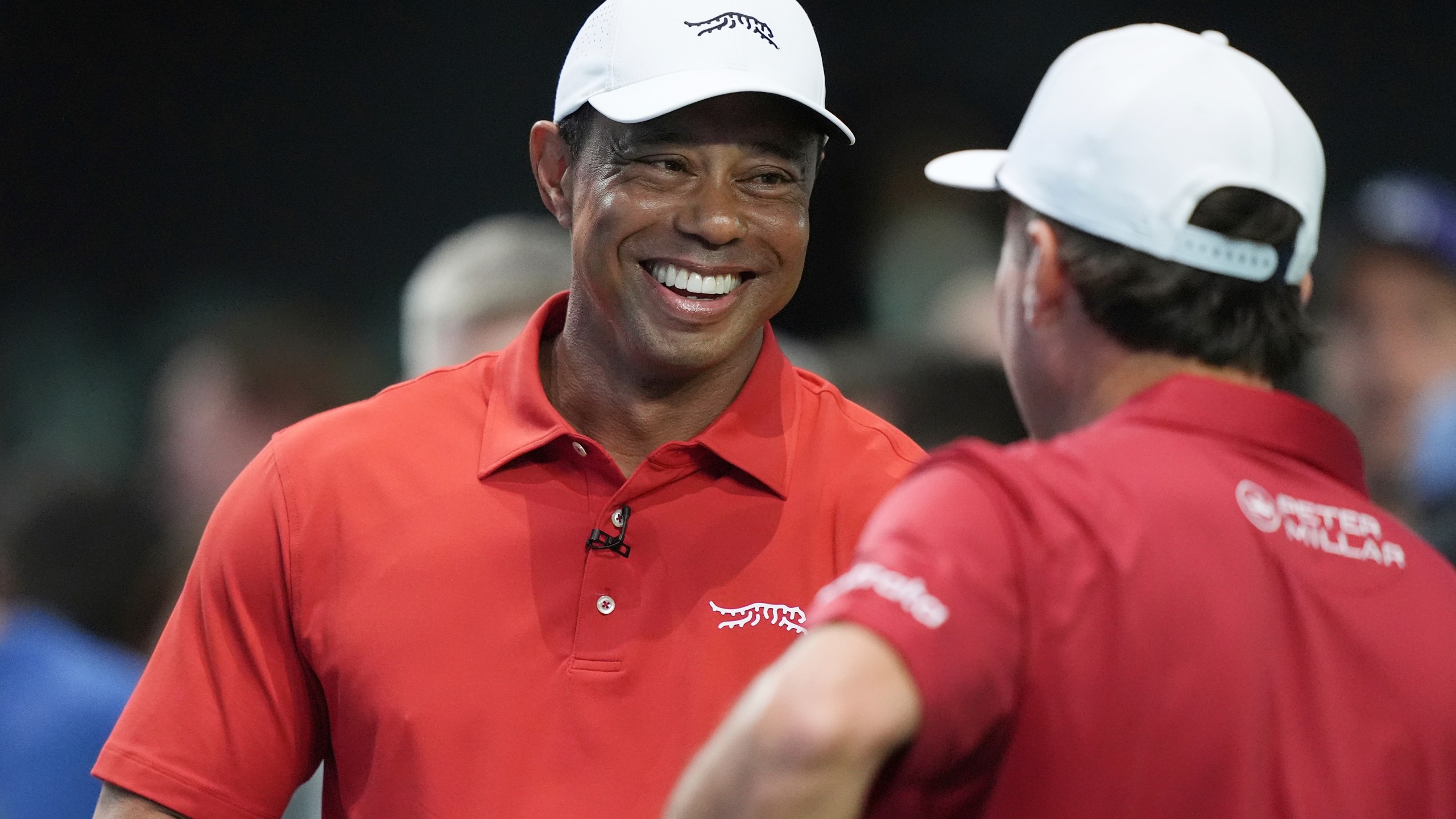 Tiger Woods talks to his Jupiter Links Golf Club teammate Kevin Kisner before the start of a match against the Los Angeles Golf Club, Tuesday, Jan. 14, 2025, in Palm Beach Gardens, Fla. TGL featured two teams of three players competing against each other in a tech-infused arena the size of a football field. (AP Photo/Marta Lavandier)