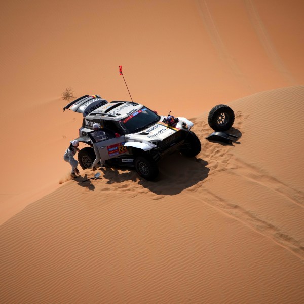 Driver Guillaume De Mevius and co-driver Mathieu Baumel repair a wheel during the tenth stage of the Dakar Rally between Haradh and Shubaytah, Saudi Arabia, Wednesday, Jan. 15, 2025. (AP Photo/Christophe Ena)