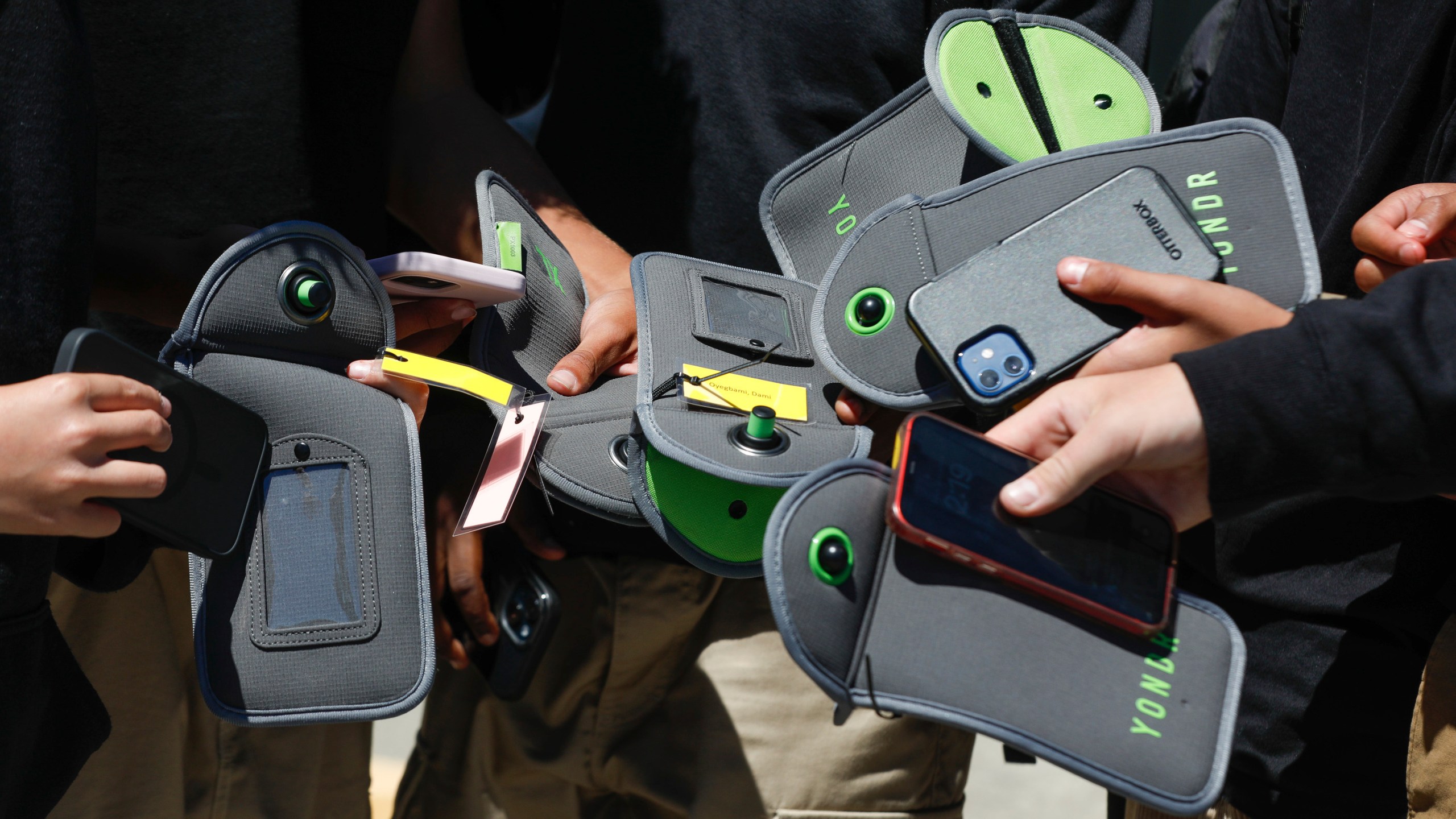 FILE - A student uses a cell phone after unlocking the pouch that secures it from use during the school day at Bayside Academy, Aug. 16, 2024, in San Mateo, Calif. (Lea Suzuki/San Francisco Chronicle via AP, File)