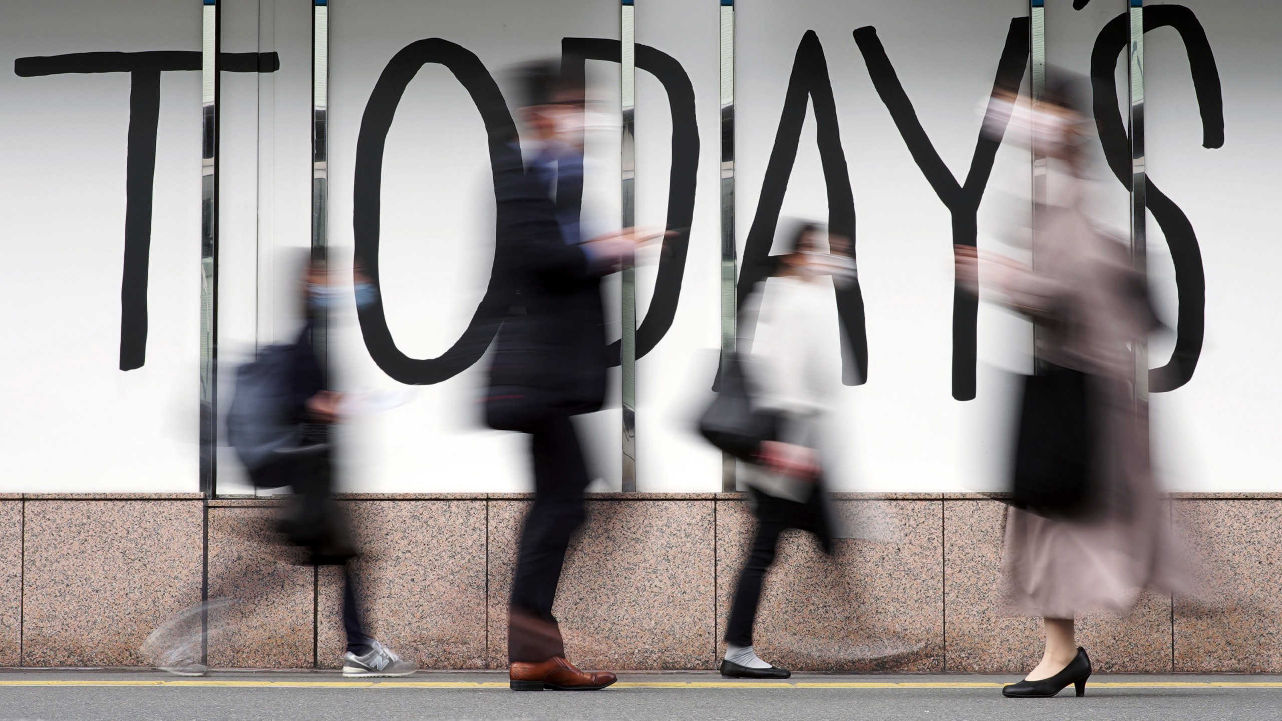 FILE - People wearing face masks walk along a street April 7, 2022, in Tokyo. (AP Photo/Eugene Hoshiko, File)