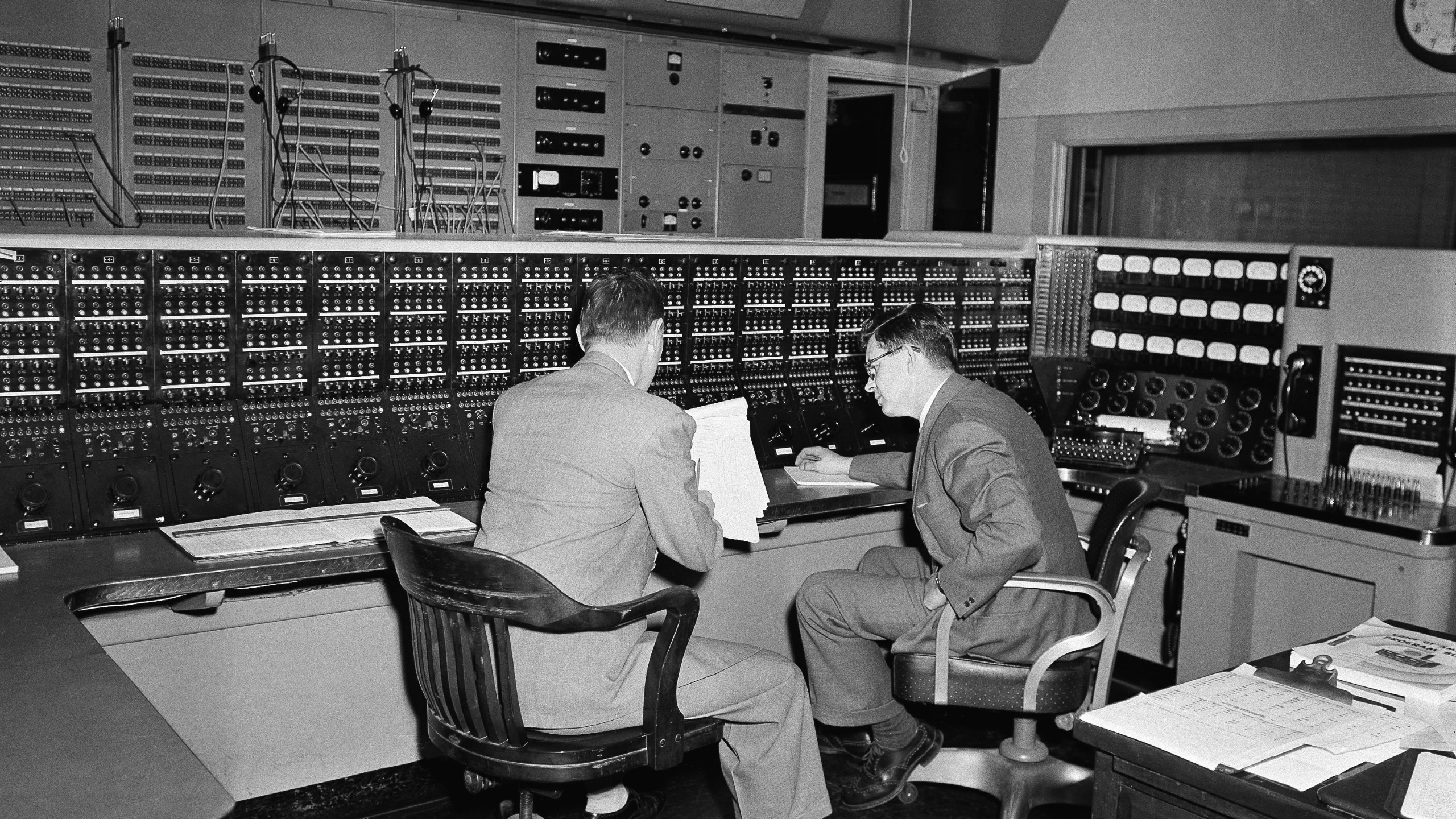 FILE - Two employees huddle in the Voice of America's radio control room in New York, Feb. 27, 1953, through which all voice broadcasts. (AP Photo/John Rooney, File)